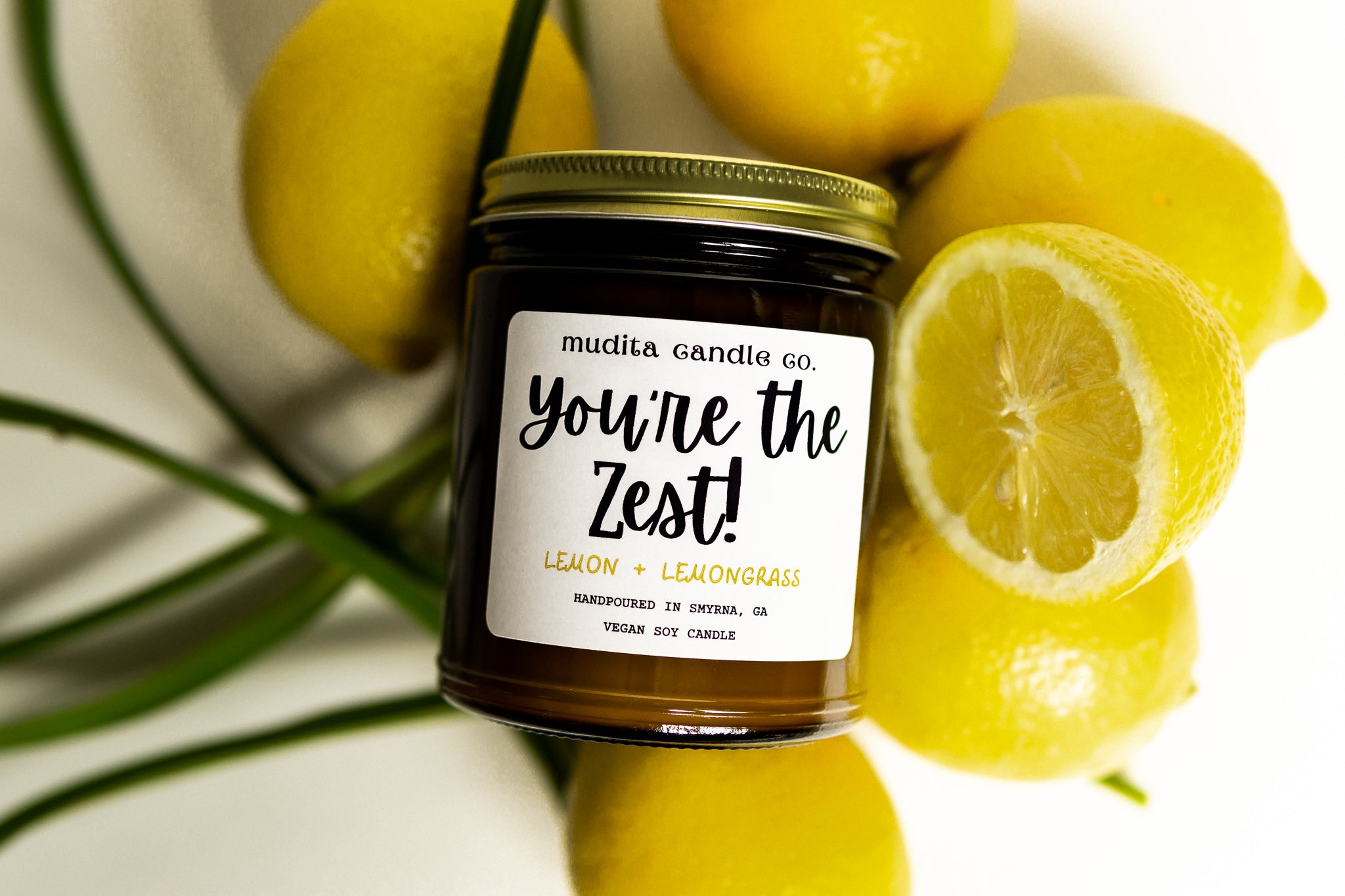 You're the Zest! candle in an amber glass jar with a gold lid, featuring a citrusy lemon and fresh lemongrass scent.