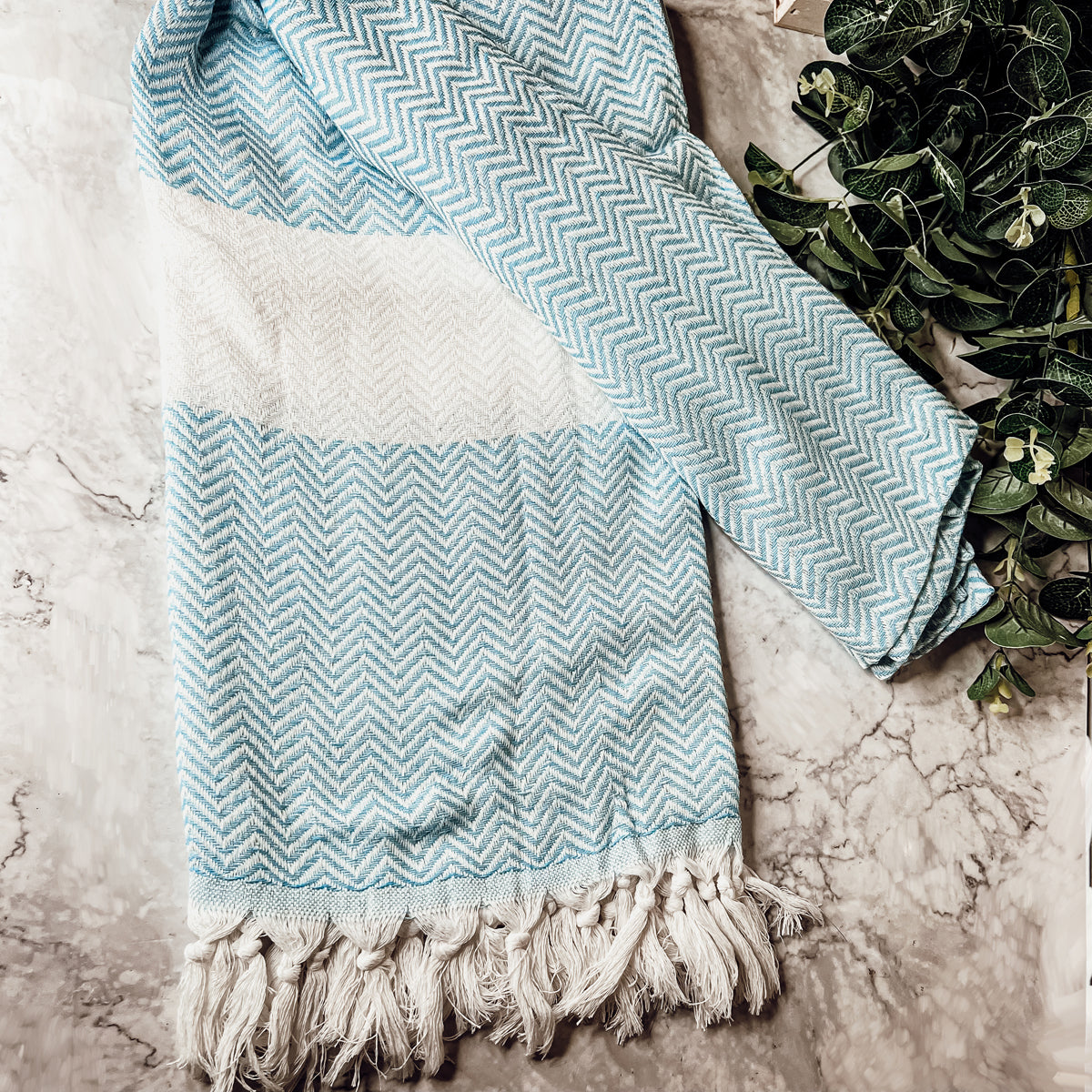 Chevron Towel made from 200 GSM Turkish cotton, featuring decorative tassels and available in blue, gray, and rust colors.