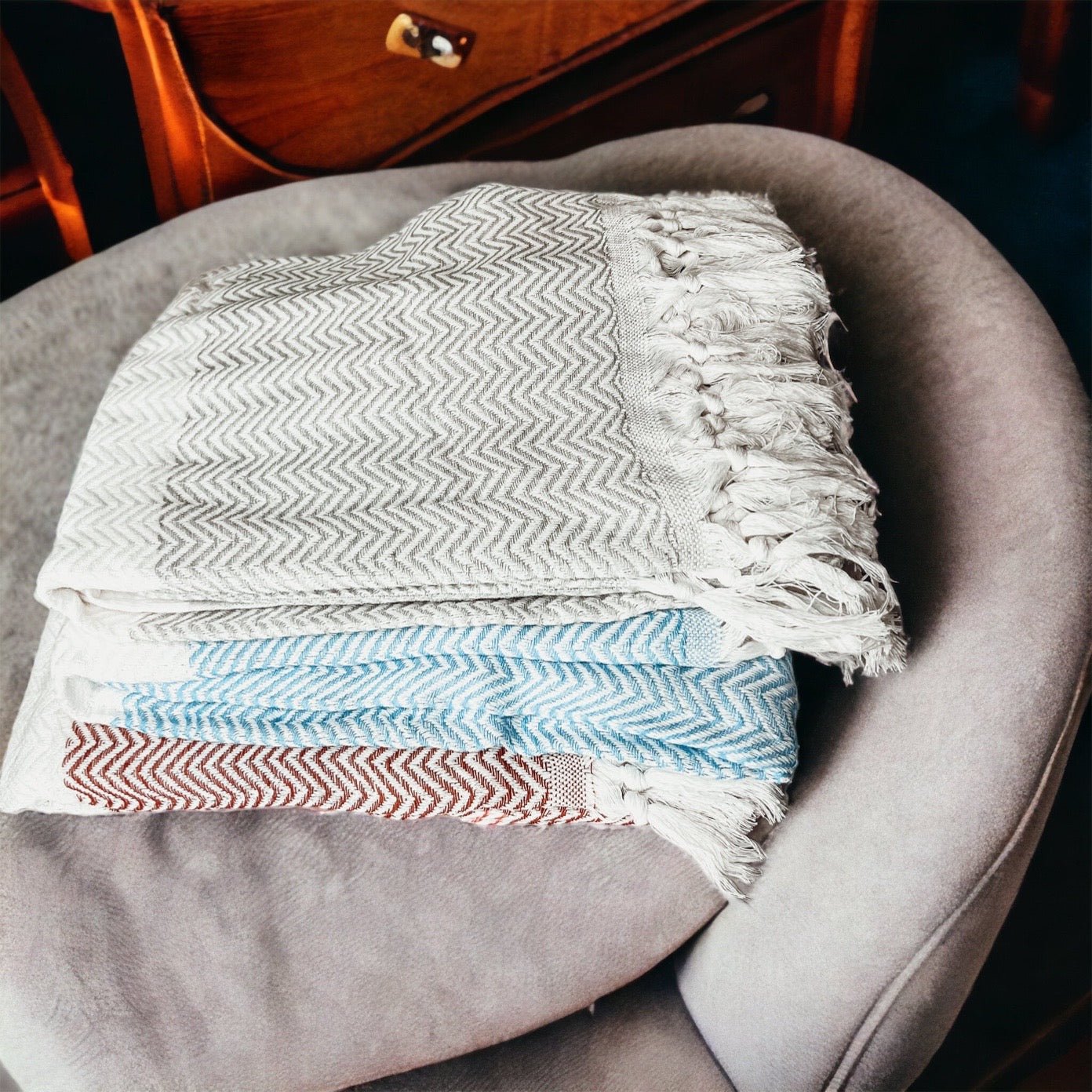 Chevron Towel made from 200 GSM Turkish cotton, featuring decorative tassels and available in blue, gray, and rust colors.