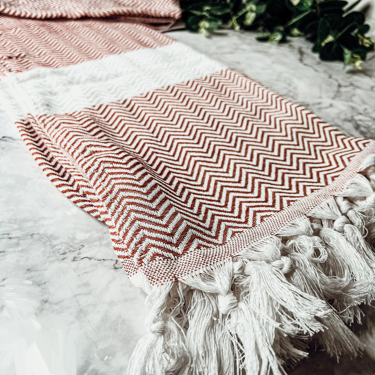 Chevron Towel made from 200 GSM Turkish cotton, featuring decorative tassels and available in blue, gray, and rust colors.