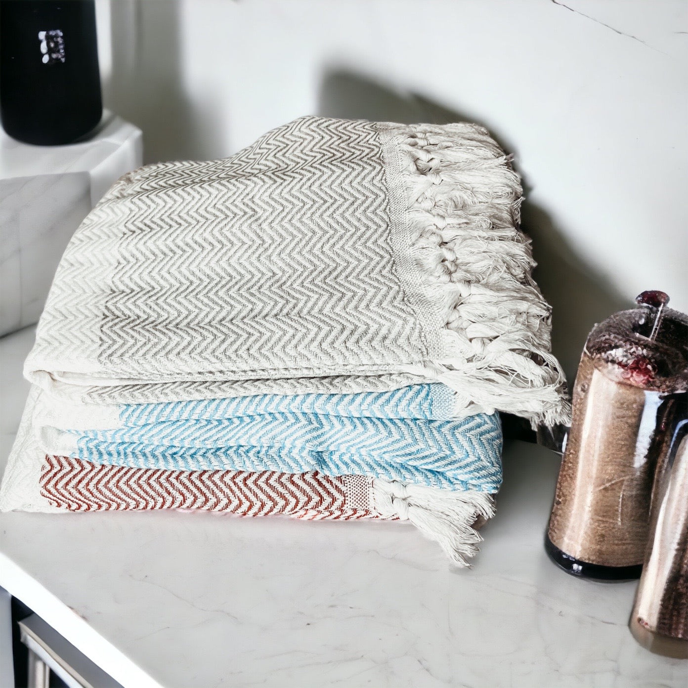 Chevron Towel made from 200 GSM Turkish cotton, featuring decorative tassels and available in blue, gray, and rust colors.