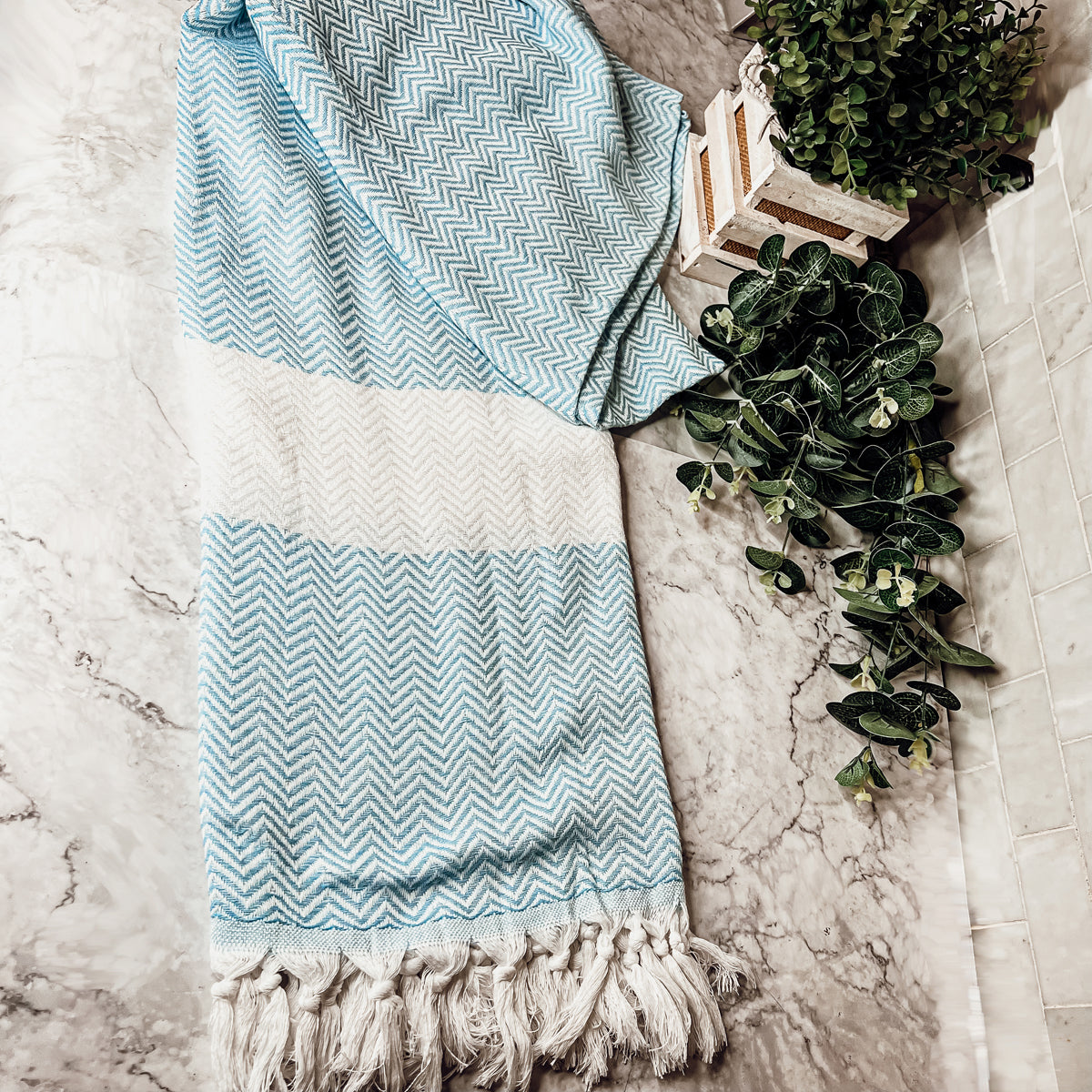 Chevron Towel made from 200 GSM Turkish cotton, featuring decorative tassels and available in blue, gray, and rust colors.