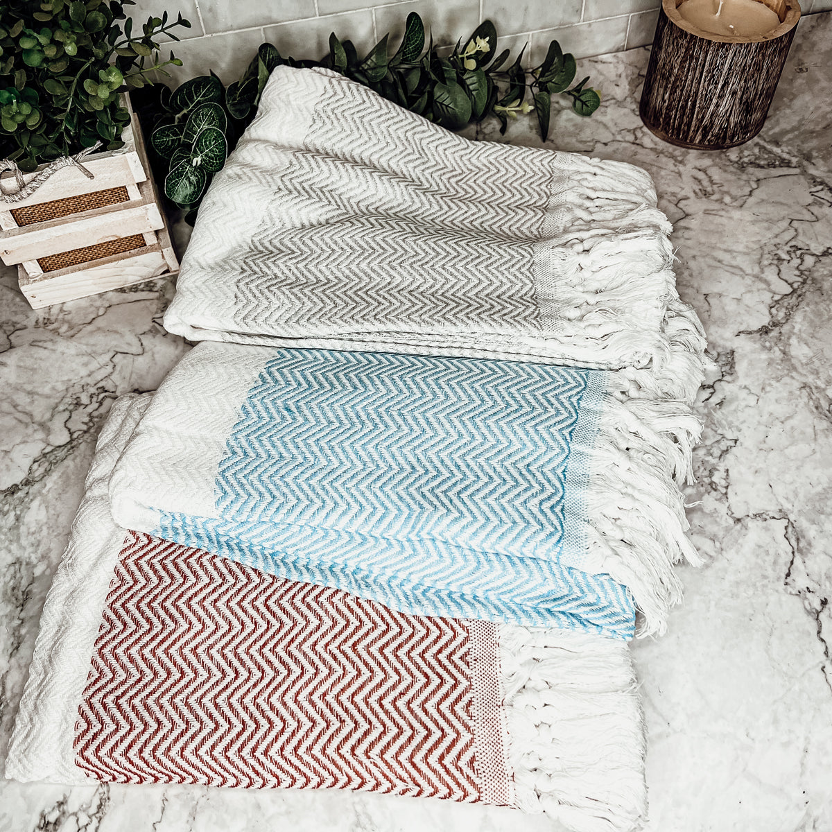 Chevron Towel made from 200 GSM Turkish cotton, featuring decorative tassels and available in blue, gray, and rust colors.