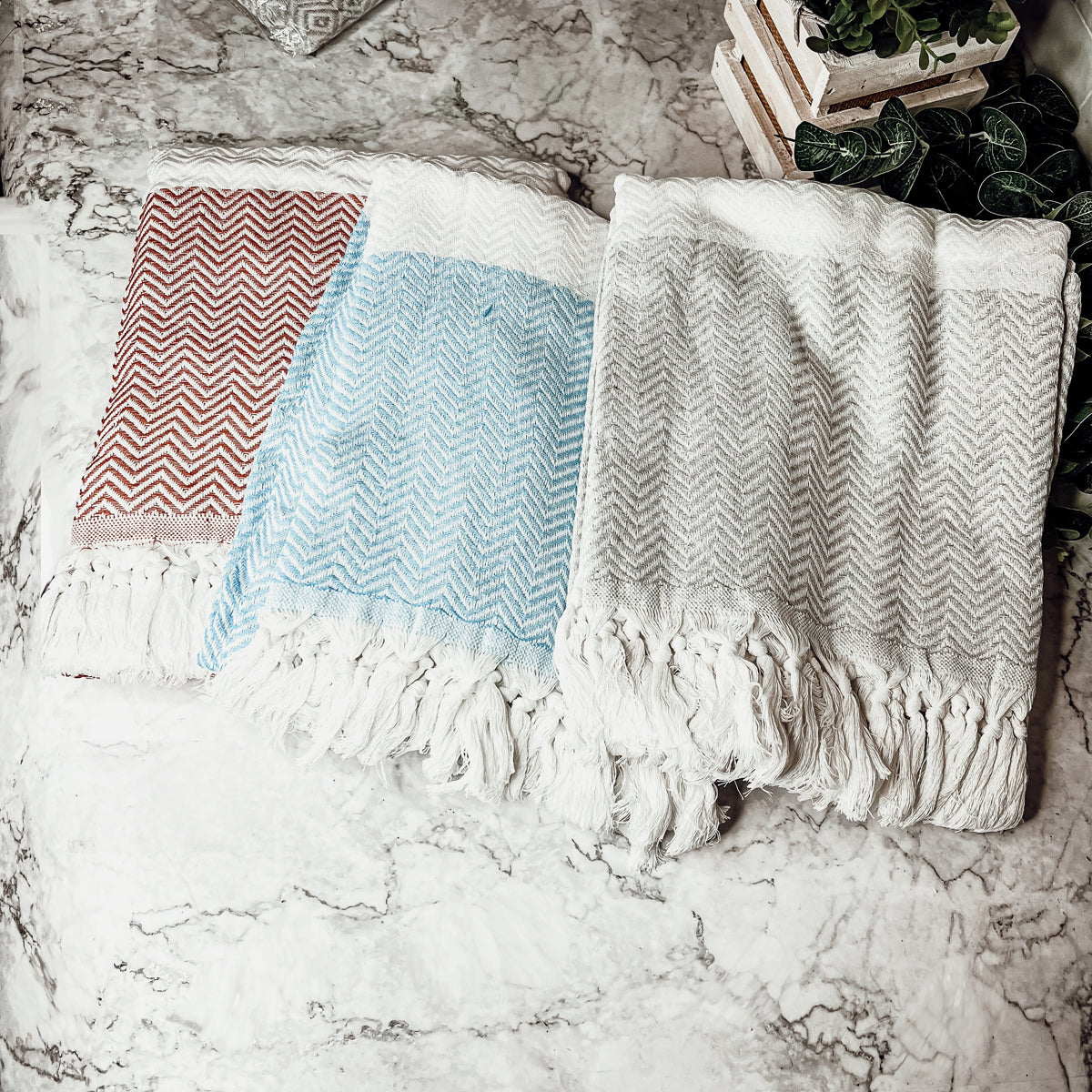 Chevron Towel made from 200 GSM Turkish cotton, featuring decorative tassels and available in blue, gray, and rust colors.