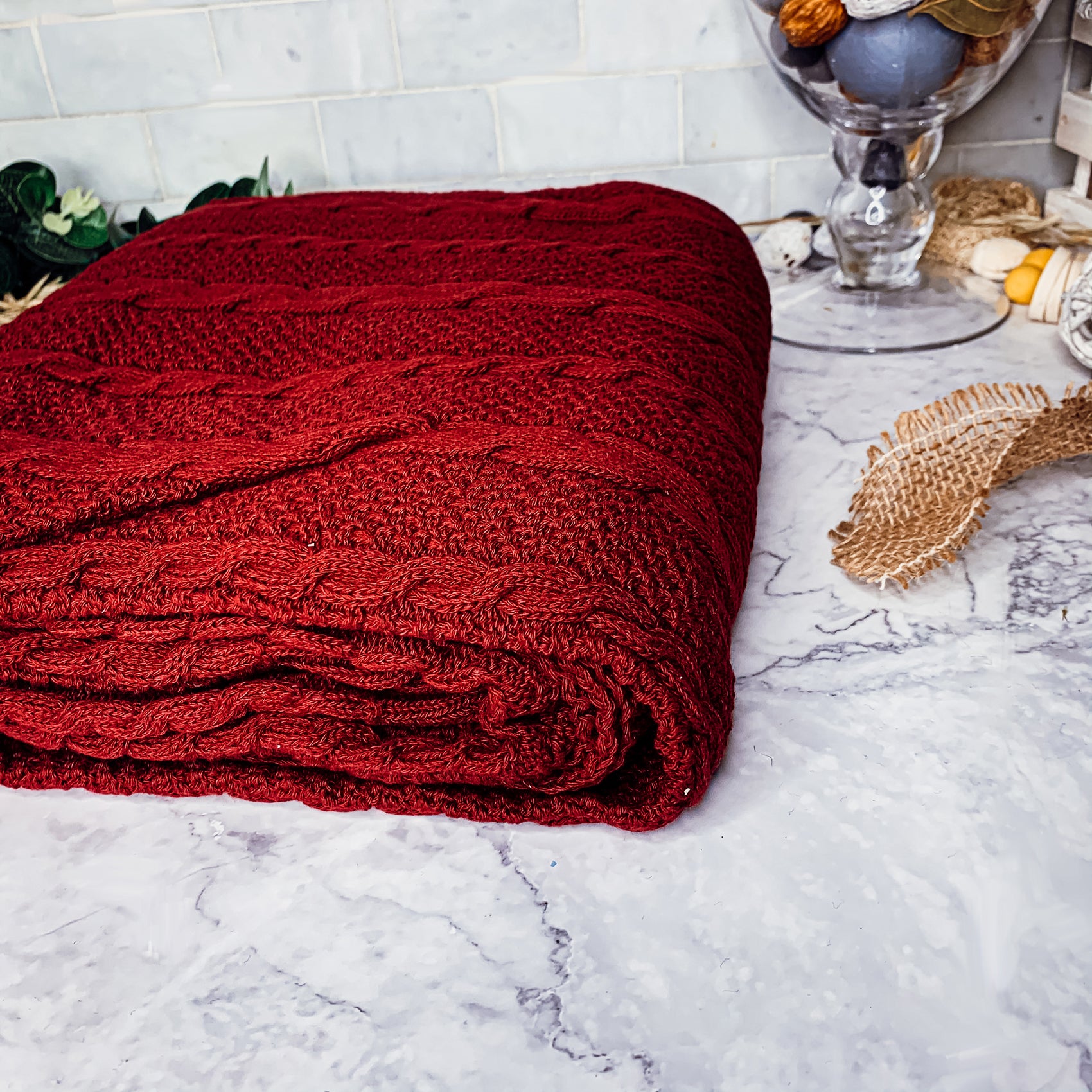 Cozy Claret Knit Sweater Throw blanket draped elegantly on a couch, showcasing its rich color and soft texture.