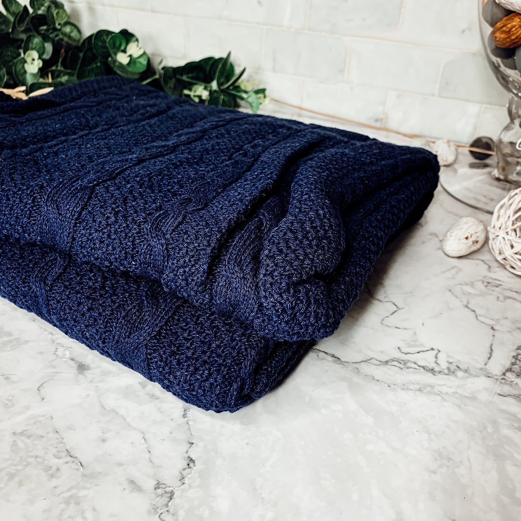 Cozy Claret Knit Sweater Throw blanket draped elegantly on a couch, showcasing its rich color and soft texture.