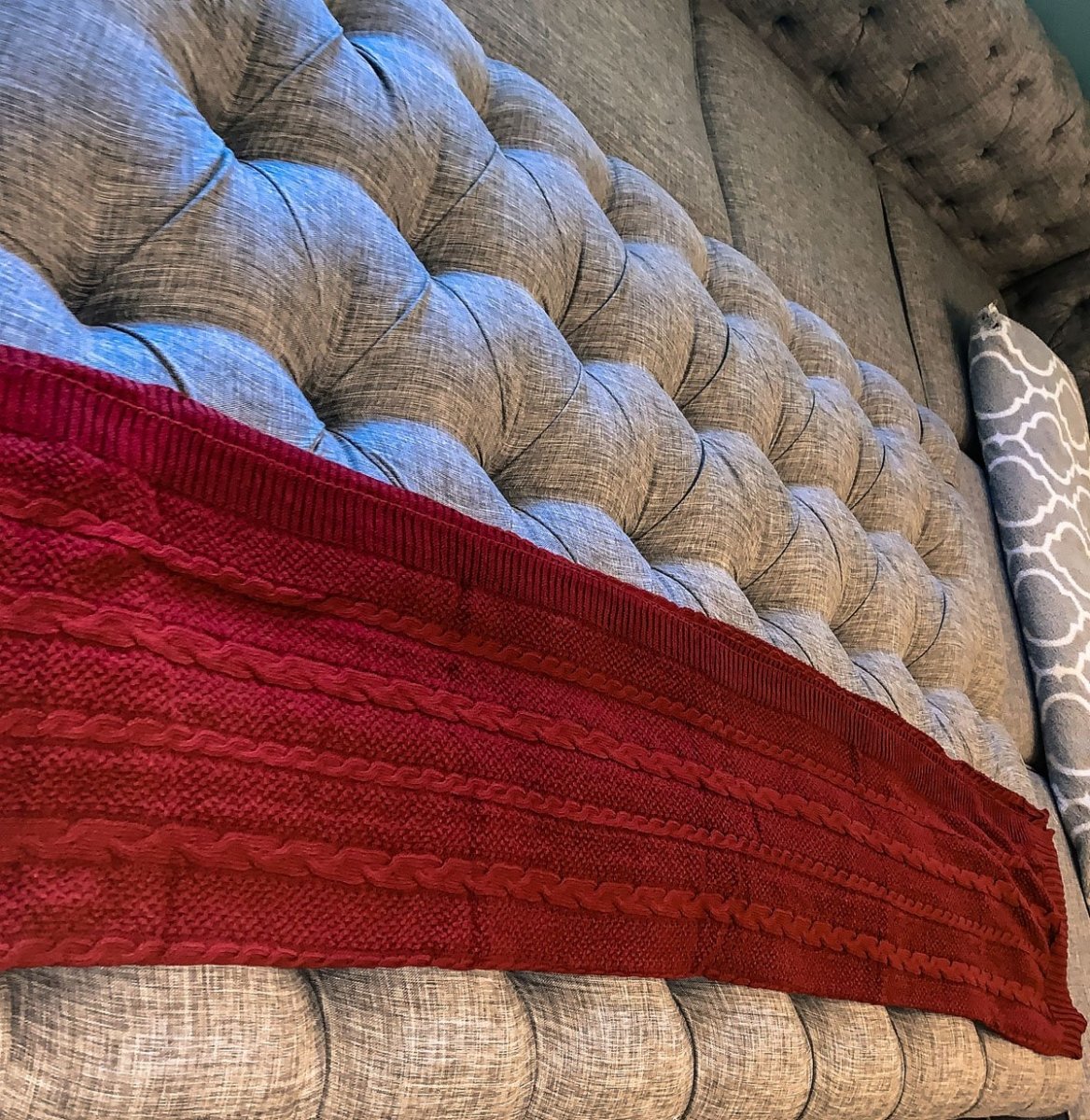 Cozy Claret Knit Sweater Throw blanket draped elegantly on a couch, showcasing its rich color and soft texture.