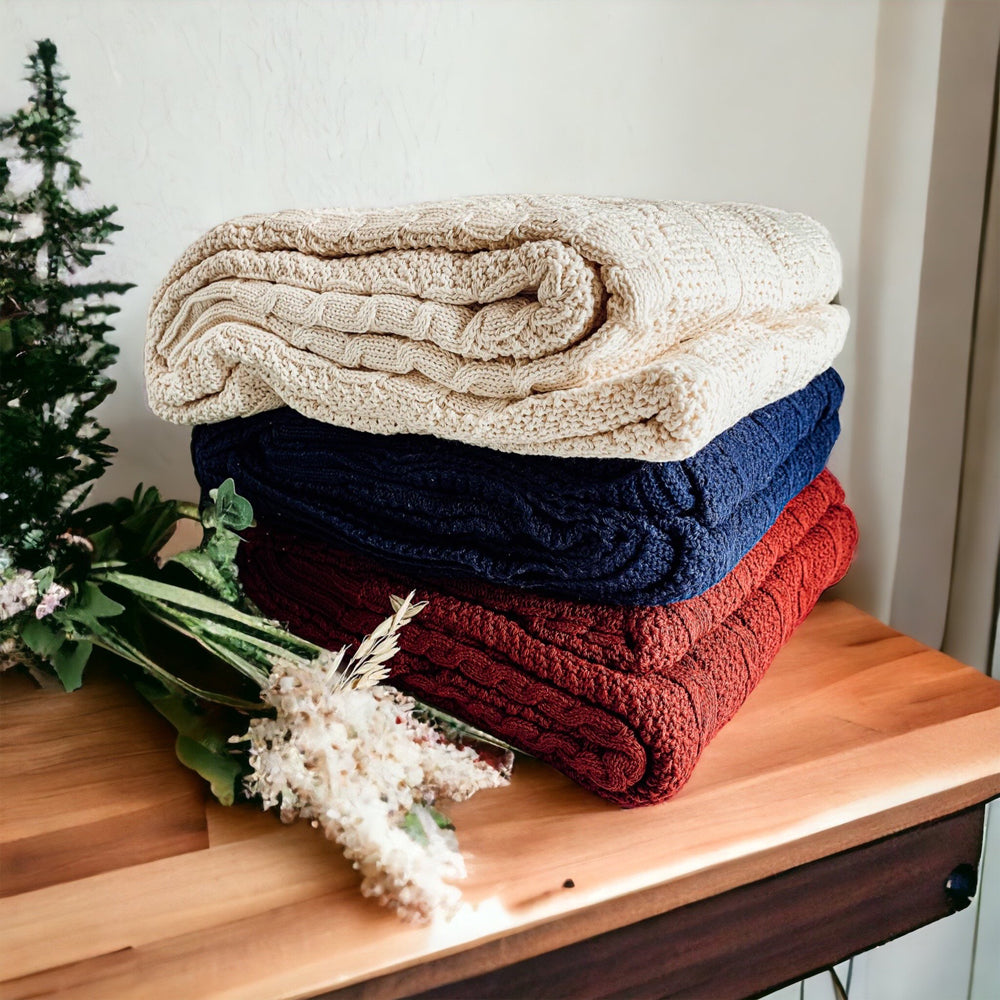 Cozy Claret Knit Sweater Throw blanket draped elegantly on a couch, showcasing its rich color and soft texture.