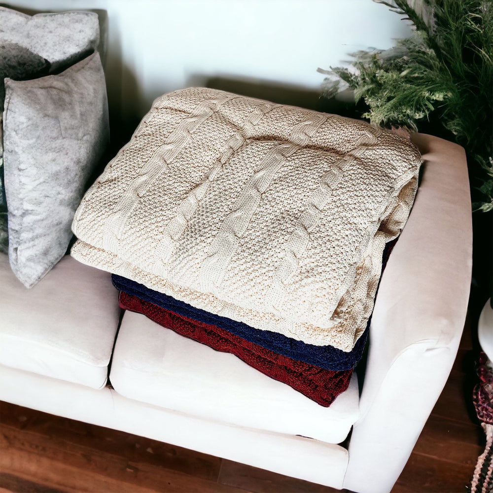 Cozy Claret Knit Sweater Throw blanket draped elegantly on a couch, showcasing its rich color and soft texture.