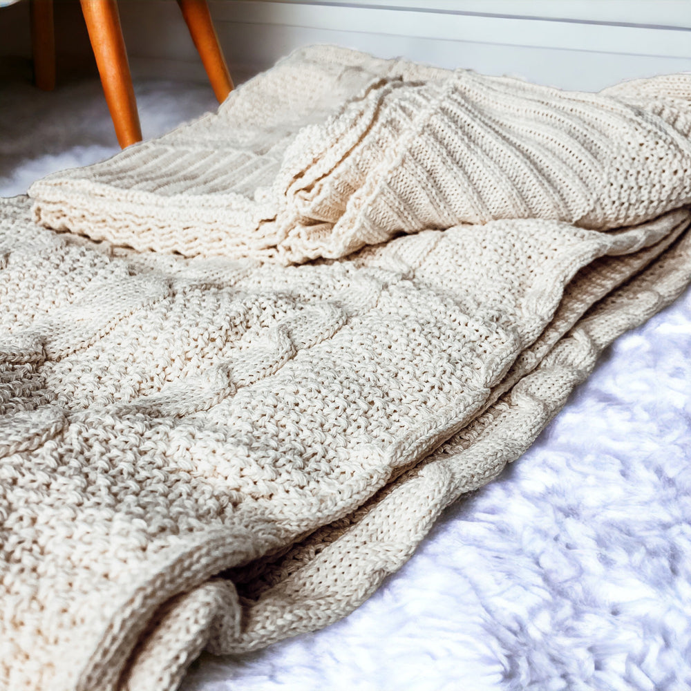 Cozy Claret Knit Sweater Throw blanket draped elegantly on a couch, showcasing its rich color and soft texture.