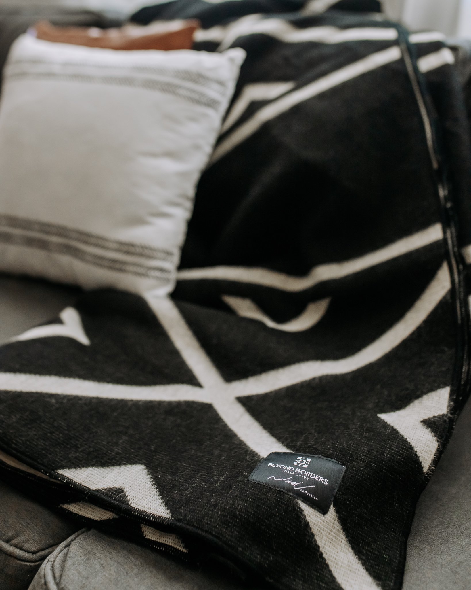 Diamante Blanket in Natural and Black, showcasing its elegant monochromatic design and soft texture, perfect for cozying up or home decor.