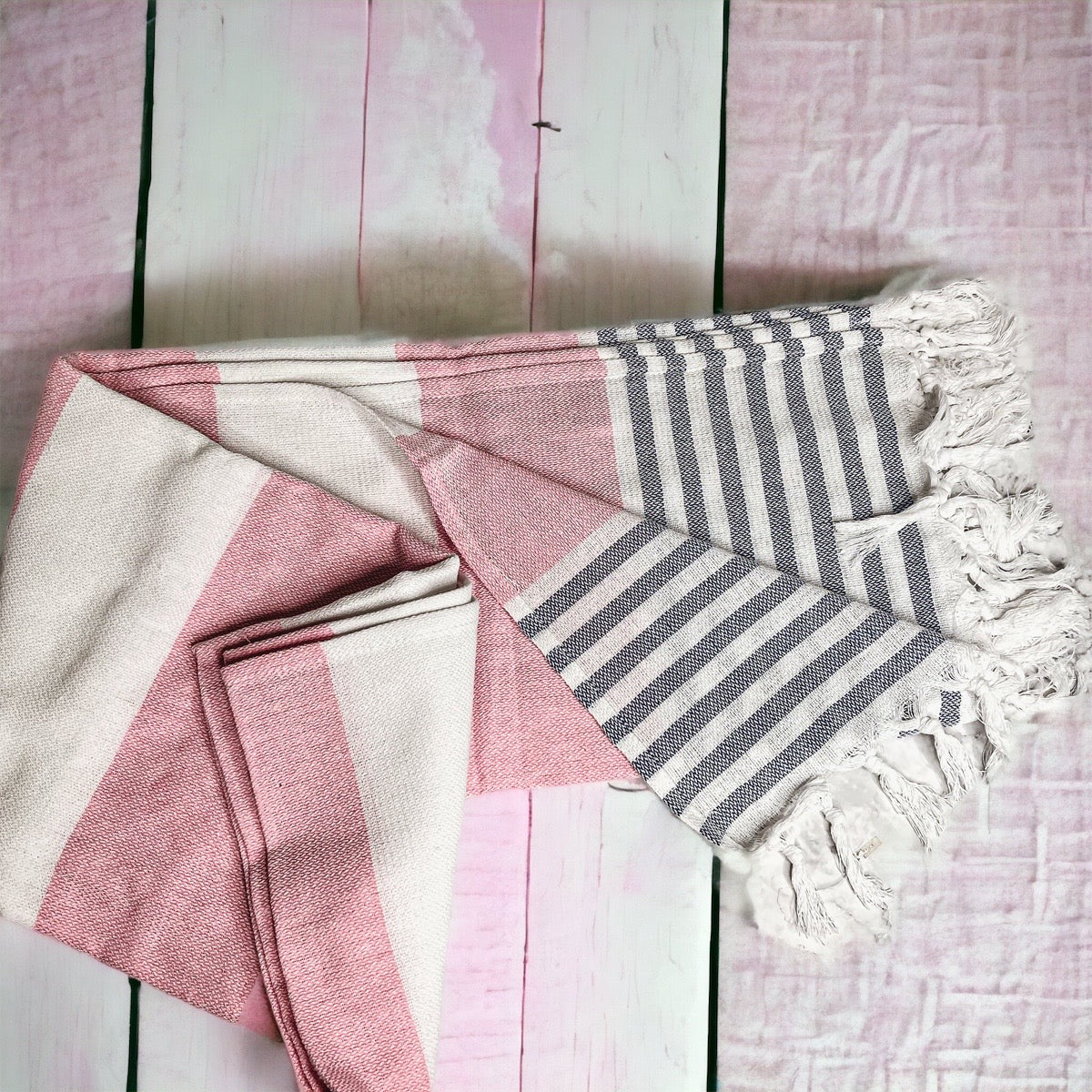 A collection of Mediterranean towels in various colors including light blue, gray, navy, and pink, featuring decorative tassels.