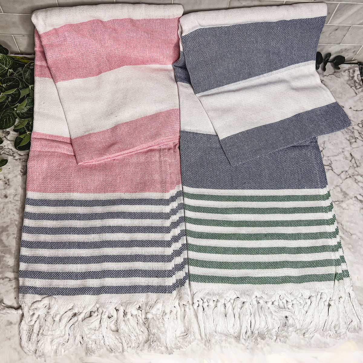 A collection of Mediterranean towels in various colors including light blue, gray, navy, and pink, featuring decorative tassels.