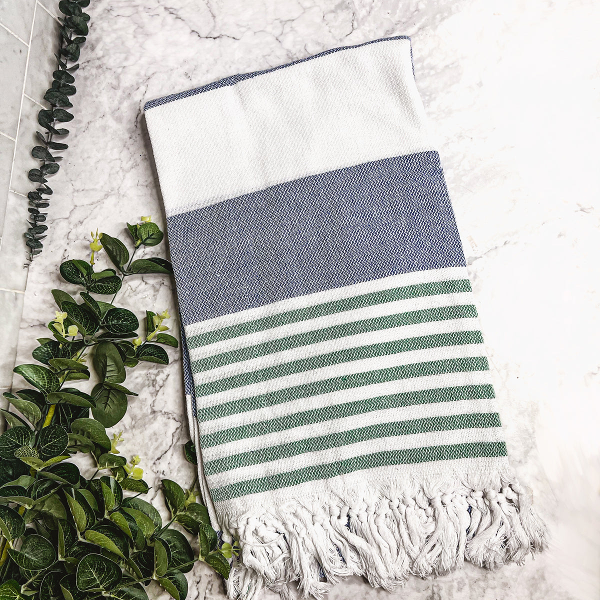 A collection of Mediterranean towels in various colors including light blue, gray, navy, and pink, featuring decorative tassels.