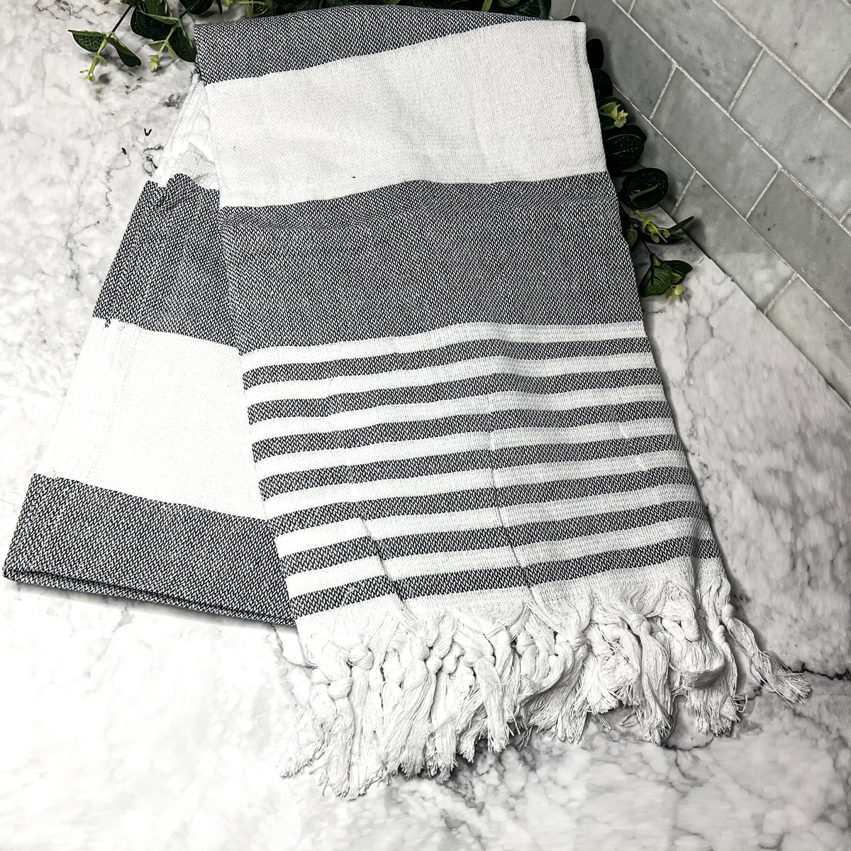 A collection of Mediterranean towels in various colors including light blue, gray, navy, and pink, featuring decorative tassels.