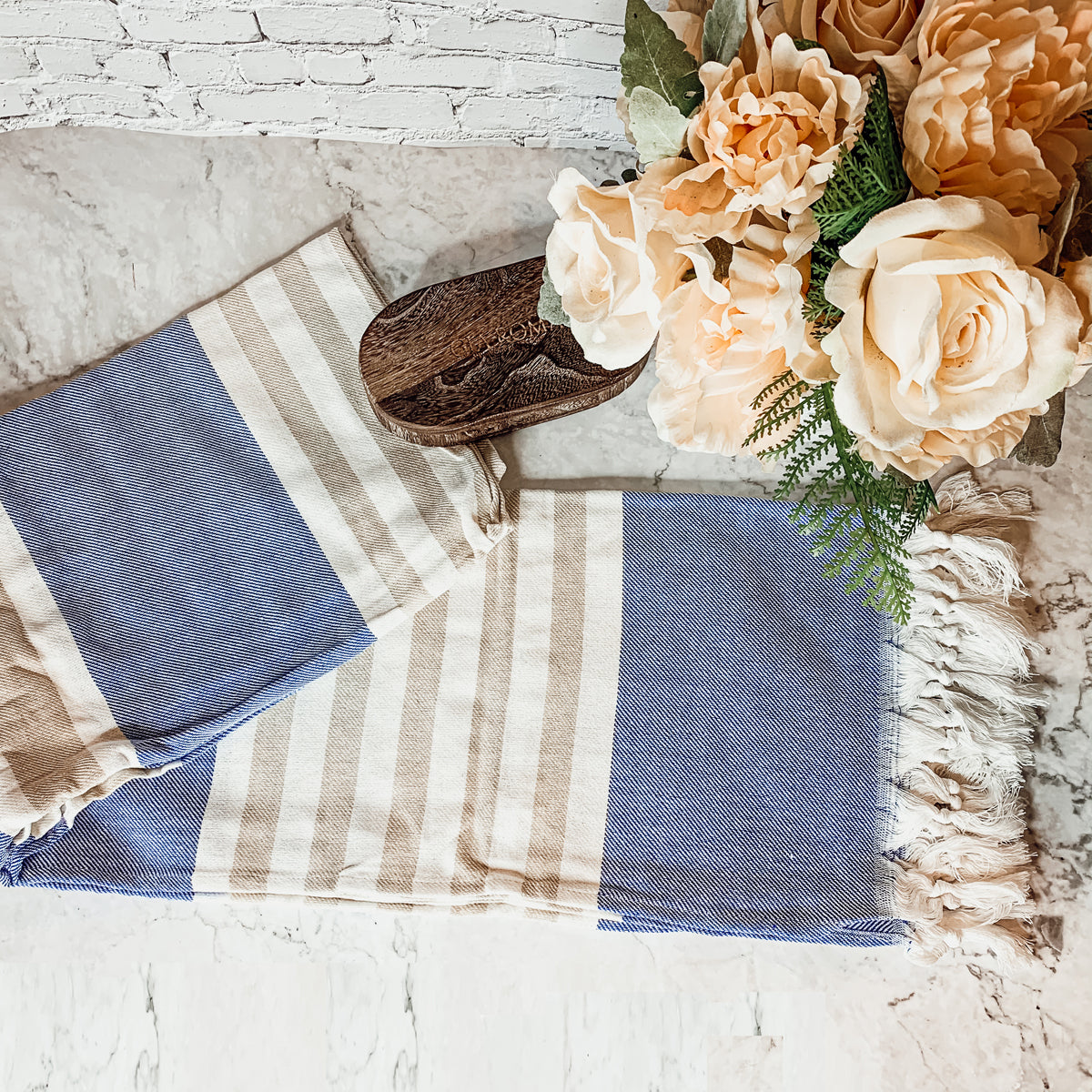 A collection of Mediterranean towels in various colors including light blue, gray, navy, and pink, featuring decorative tassels.