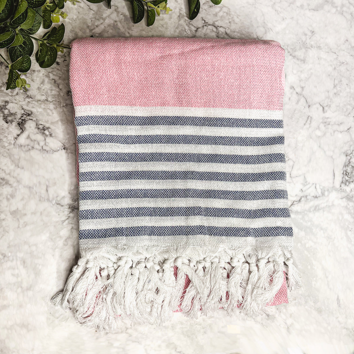 A collection of Mediterranean towels in various colors including light blue, gray, navy, and pink, featuring decorative tassels.