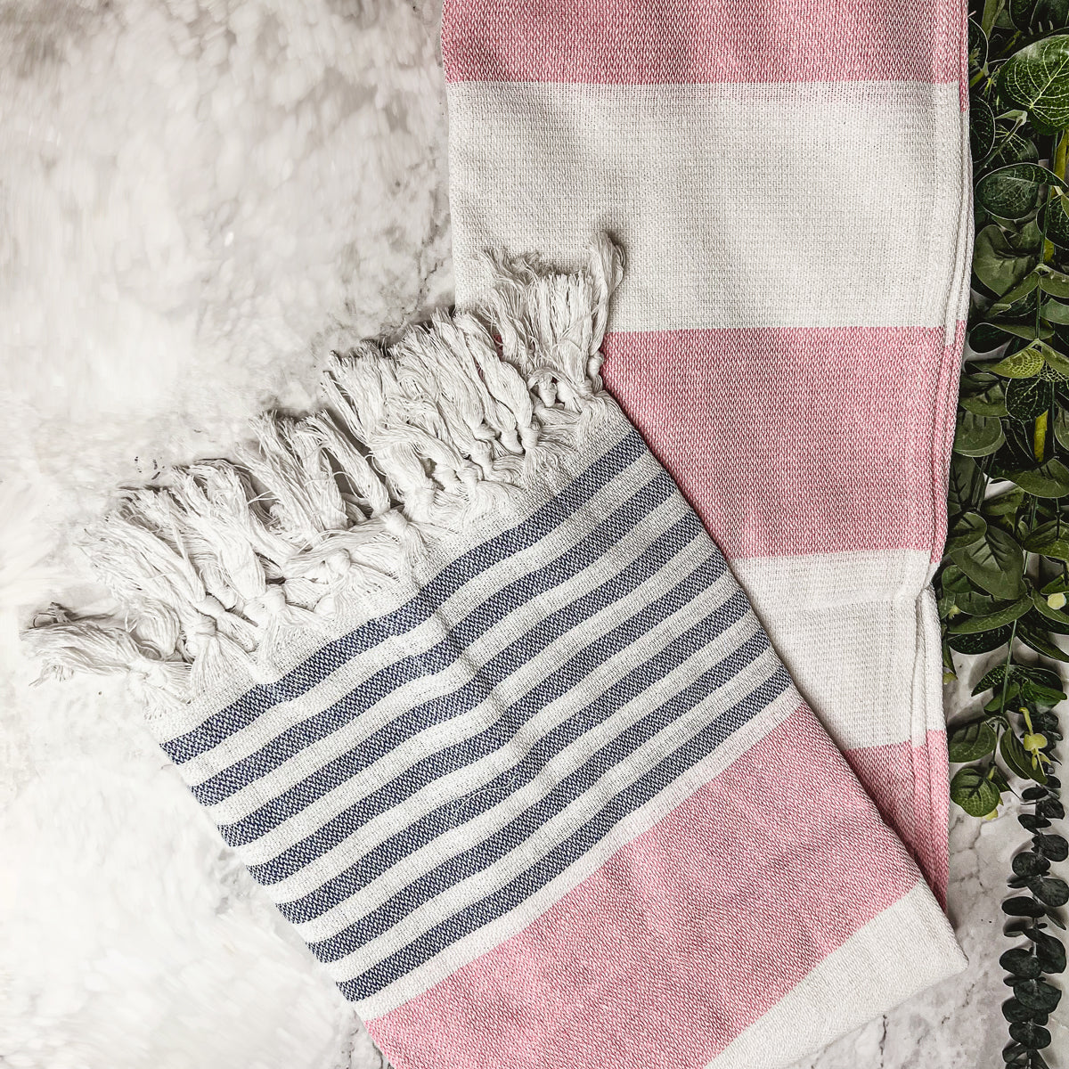 A collection of Mediterranean towels in various colors including light blue, gray, navy, and pink, featuring decorative tassels.