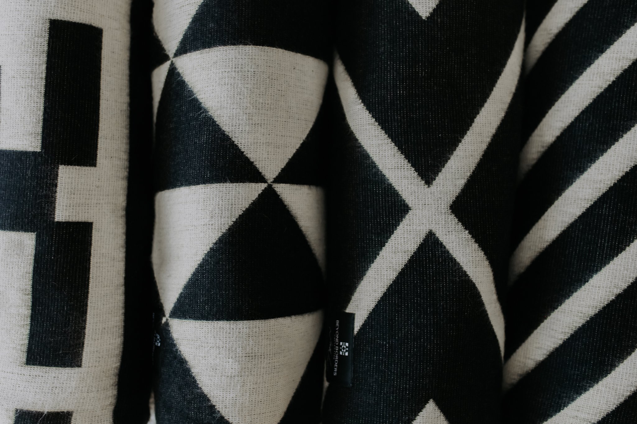 Nevado Blanket in natural and black colors, showcasing its soft texture and reversible design, perfect for cozying up or adding style to any space.