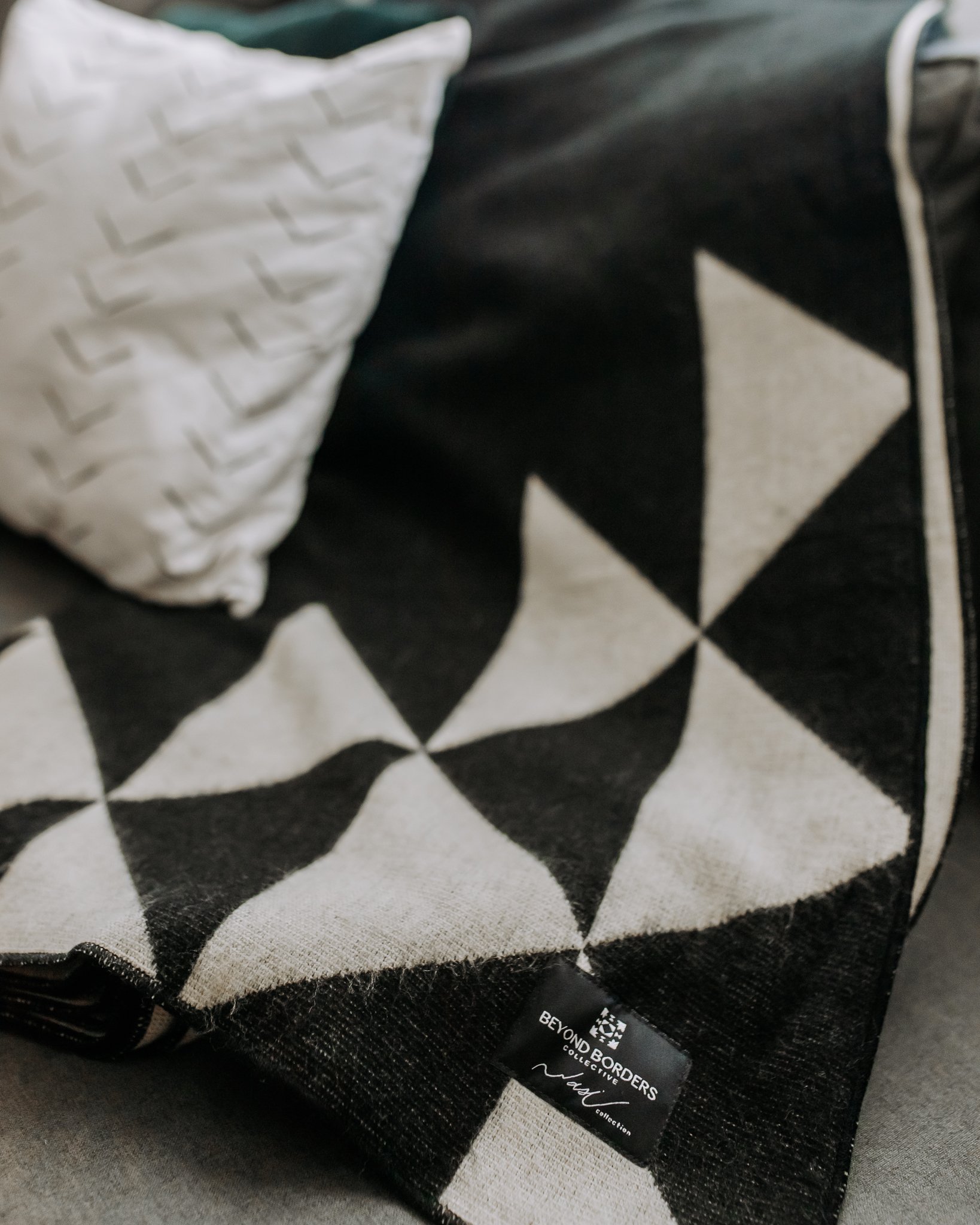 Nevado Blanket in natural and black colors, showcasing its soft texture and reversible design, perfect for cozying up or adding style to any space.