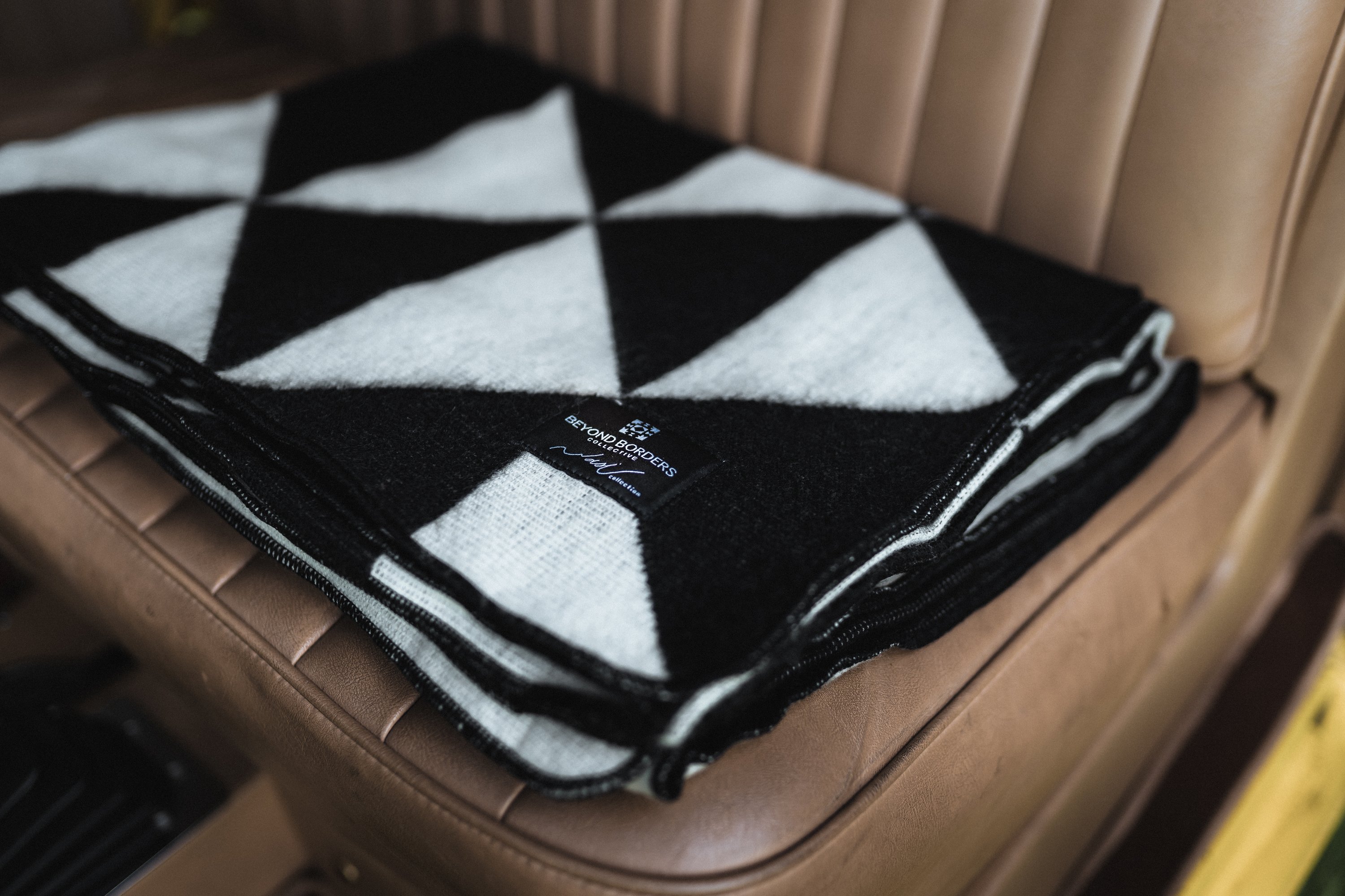 Nevado Blanket in natural and black colors, showcasing its soft texture and reversible design, perfect for cozying up or adding style to any space.