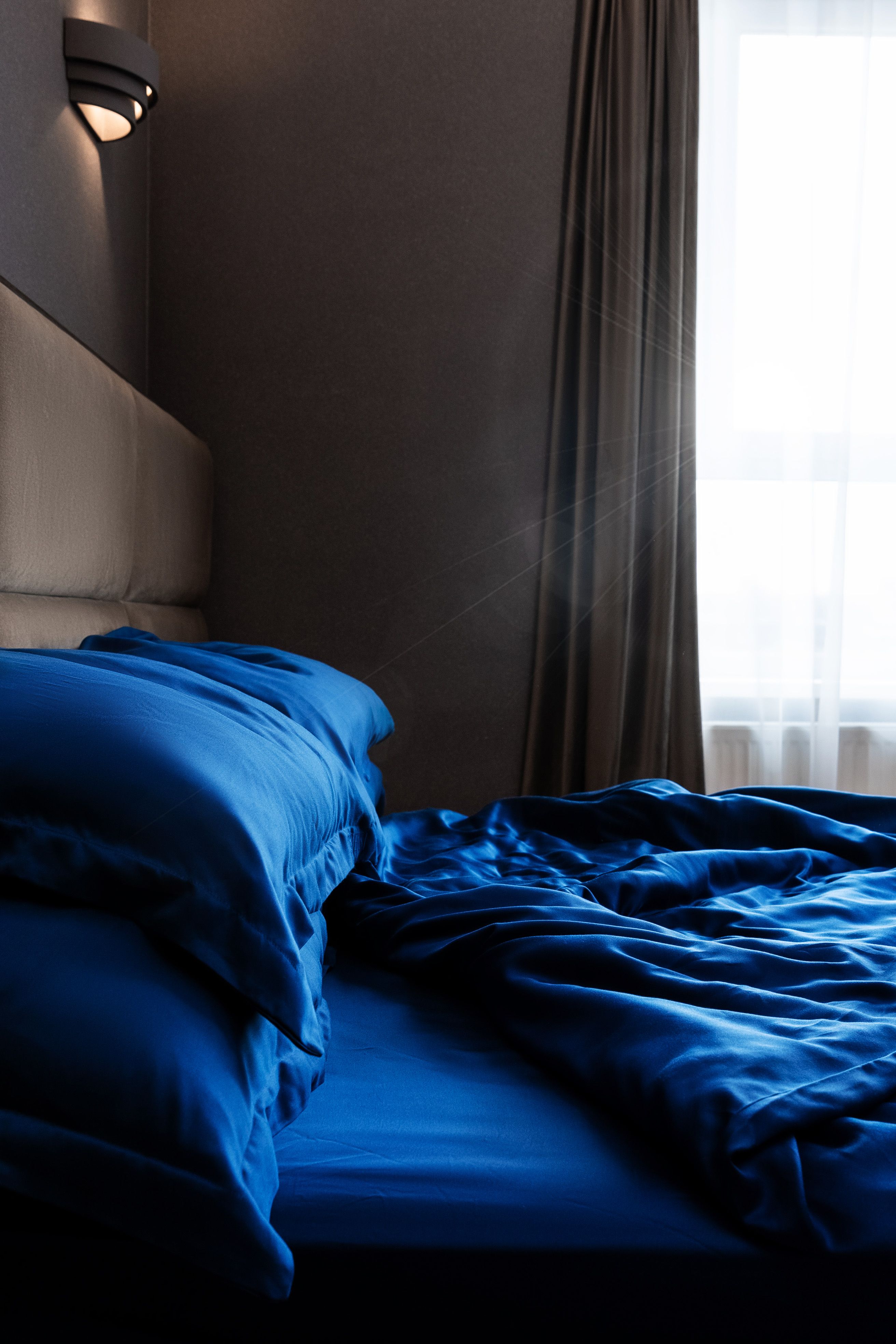 Messy bed with blue sheets.