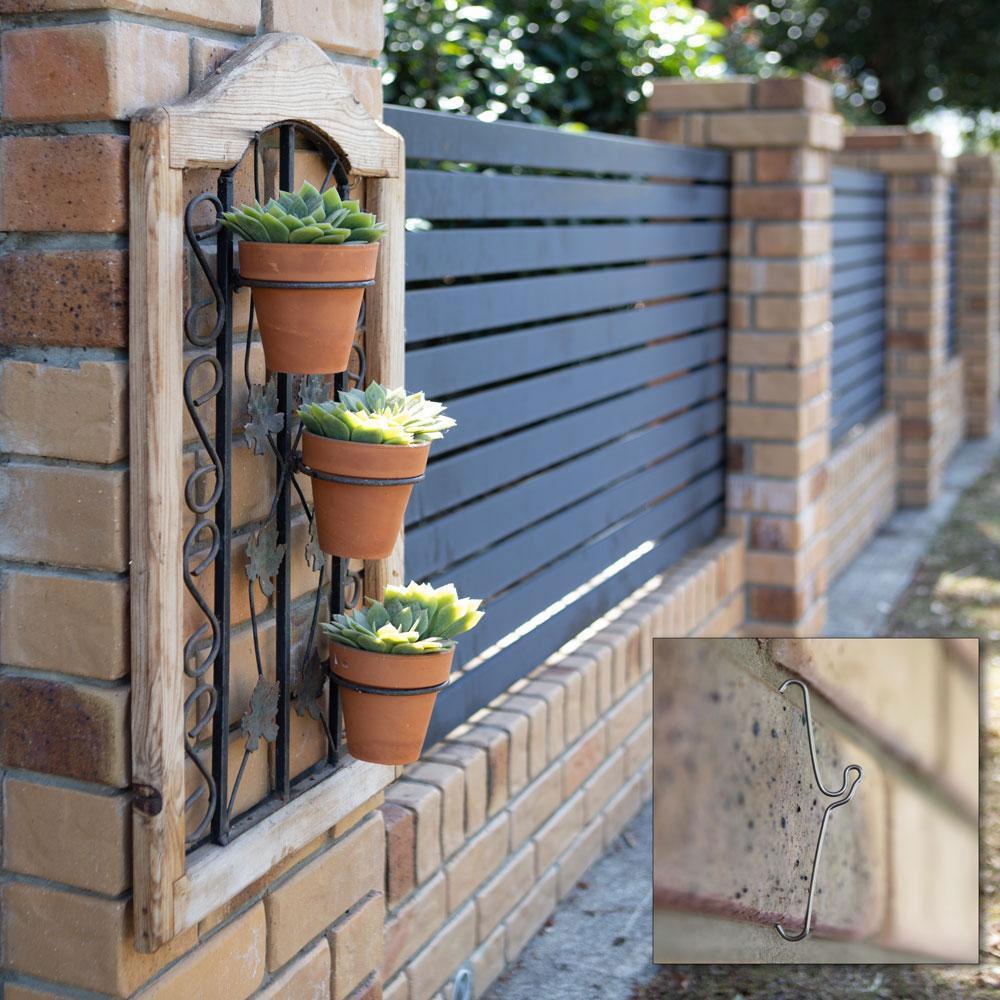 A pack of 10 Bric Crab Brick Hooks designed for hanging items on external bricks, showcasing their stainless steel construction and spring design.