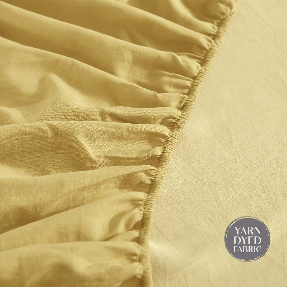 100% washed cotton bed sheet set in yellow, featuring a flat sheet, fitted sheet, and two pillow cases, showcasing a soft and breathable texture.