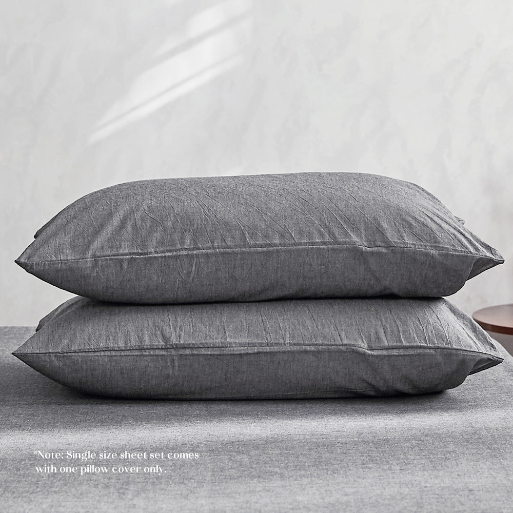 100% washed cotton sheet set in black, featuring a flat sheet, fitted sheet, and two pillowcases, showcasing a soft and breathable texture.