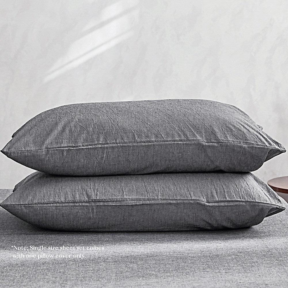 100% washed cotton sheet set in black, featuring a flat sheet, fitted sheet, and two pillow cases, showcasing a soft and elegant design.