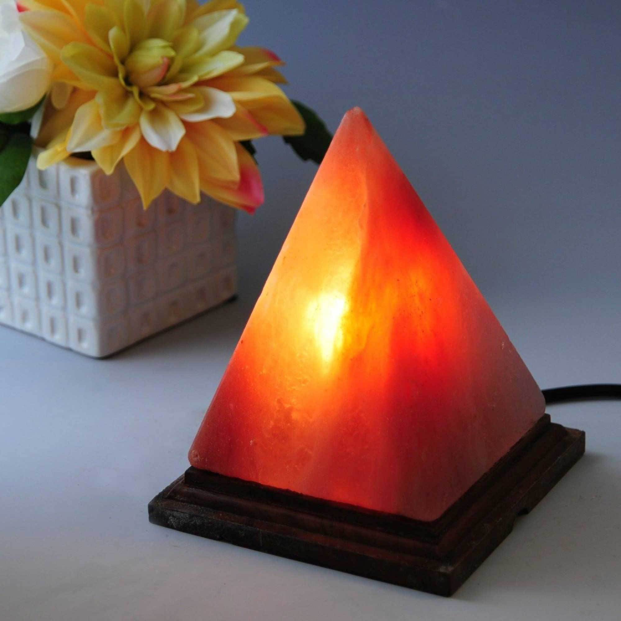 A beautifully handcrafted 12V 12W Pyramid Himalayan Pink Salt Lamp with a warm glow, showcasing its unique natural texture and wooden base.