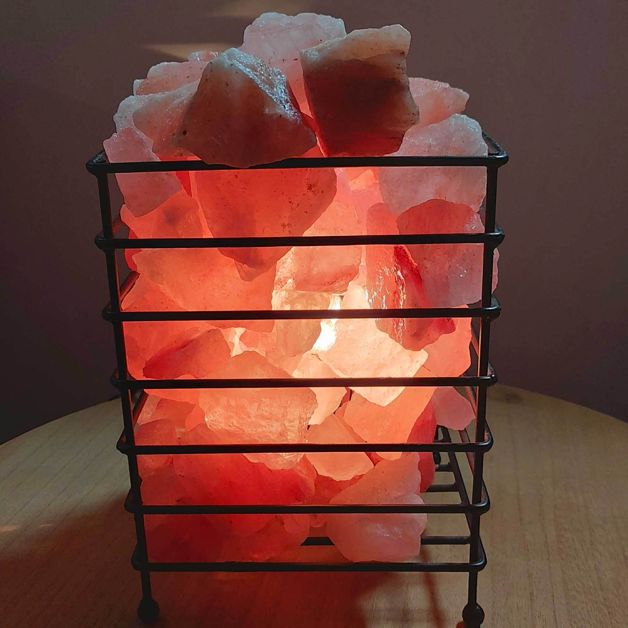 A beautifully handcrafted 12V 12W Himalayan Pink Salt Lamp in a sturdy iron basket, showcasing its natural pink hues and unique rock formations.