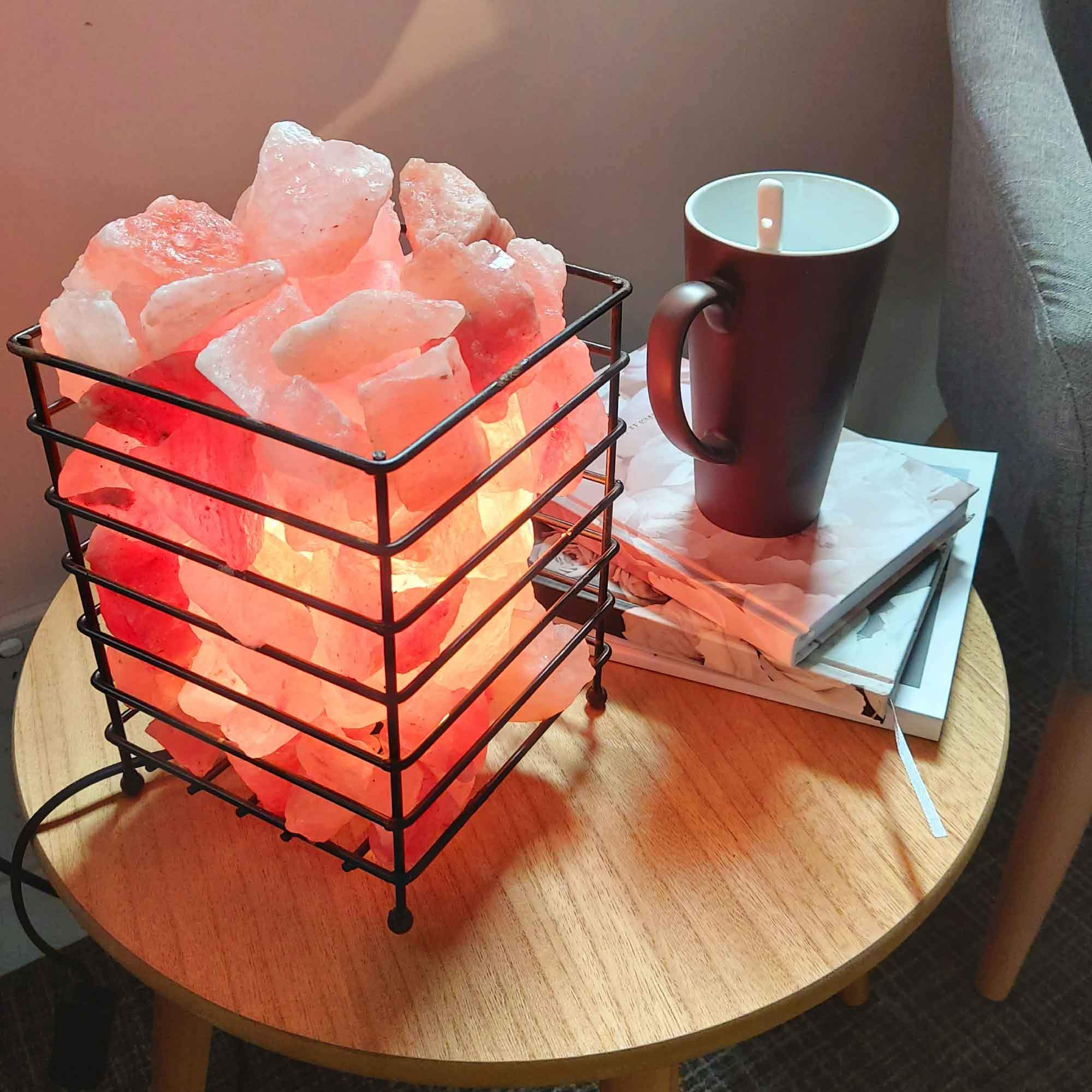 A beautifully handcrafted 12V 12W Himalayan Pink Salt Lamp in a sturdy iron basket, showcasing its natural pink hues and unique rock formations.