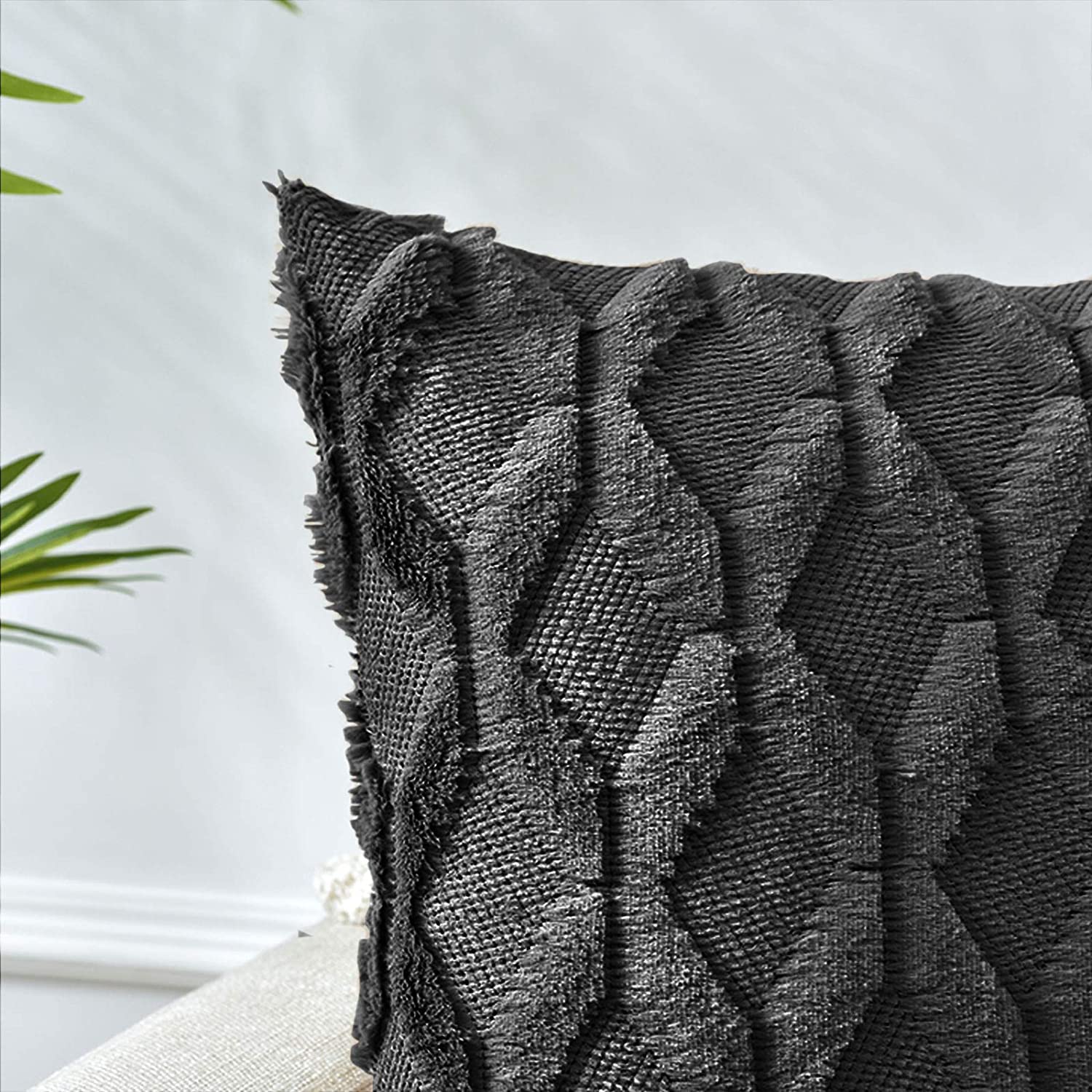 Two black decorative boho throw pillow covers with diamond design, made of soft faux fur and velvet, displayed on a cozy couch.