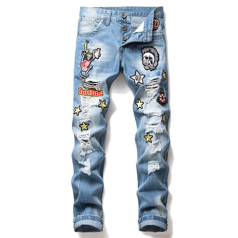 2020 New Men's Ripped Jeans featuring frayed holes and embroidered skull designs in blue denim.