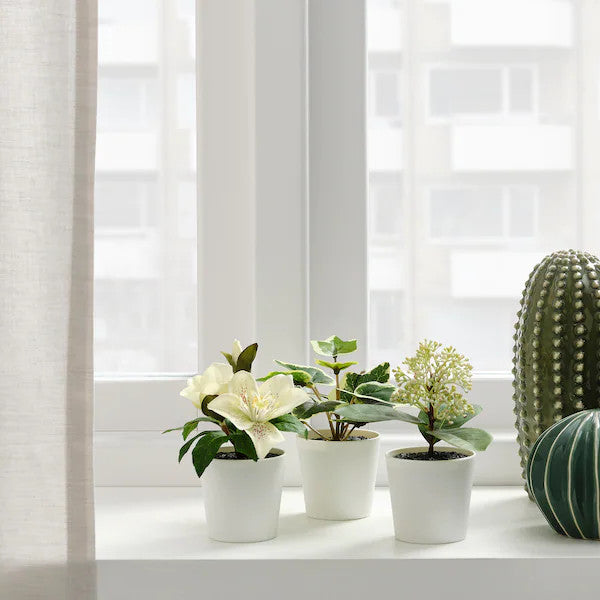 Three artificial potted plants in white plastic pots, showcasing lifelike leaves, perfect for home or office decor.