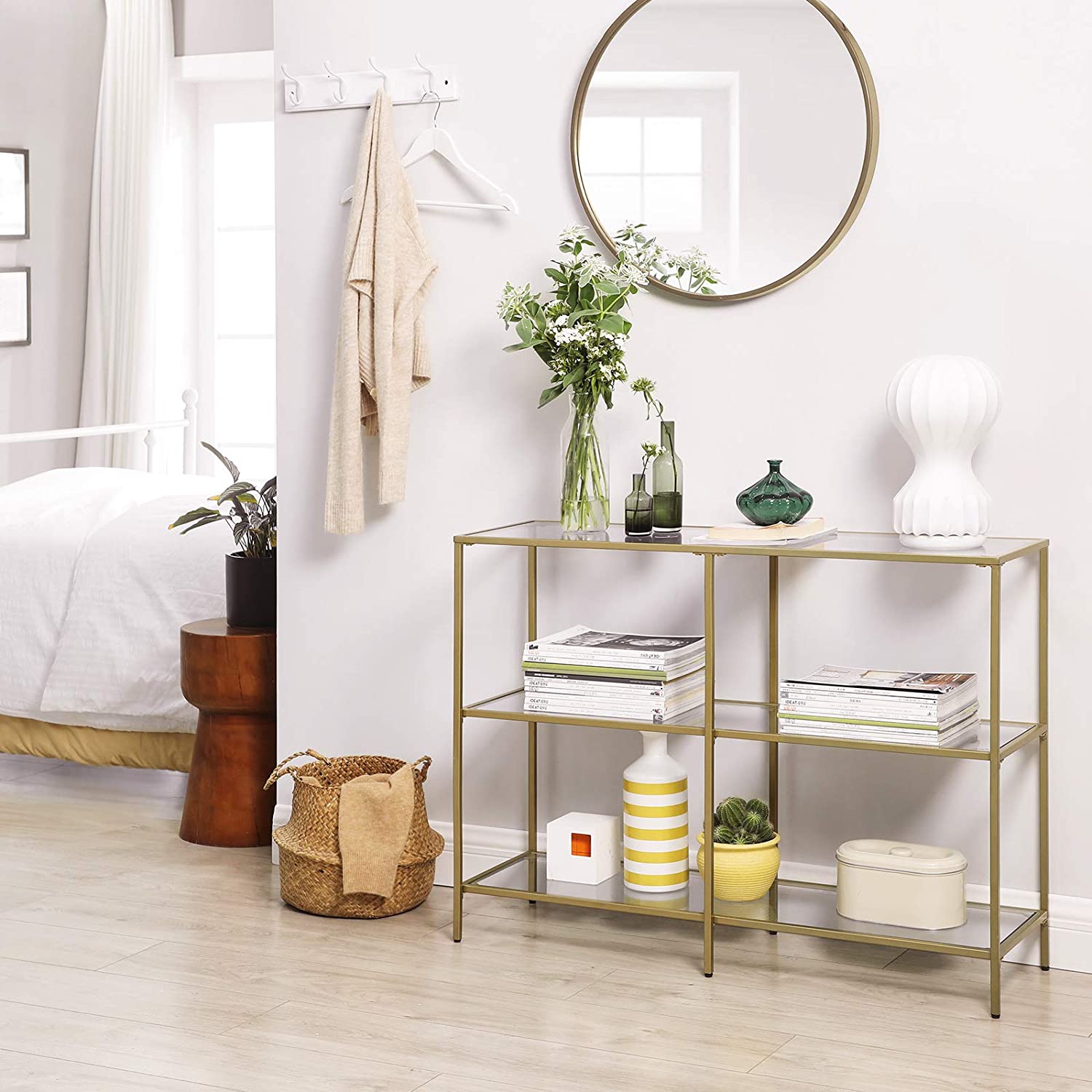 A modern 3-tier tempered glass sofa table with a sleek golden metal frame, showcasing books and decorative plants.