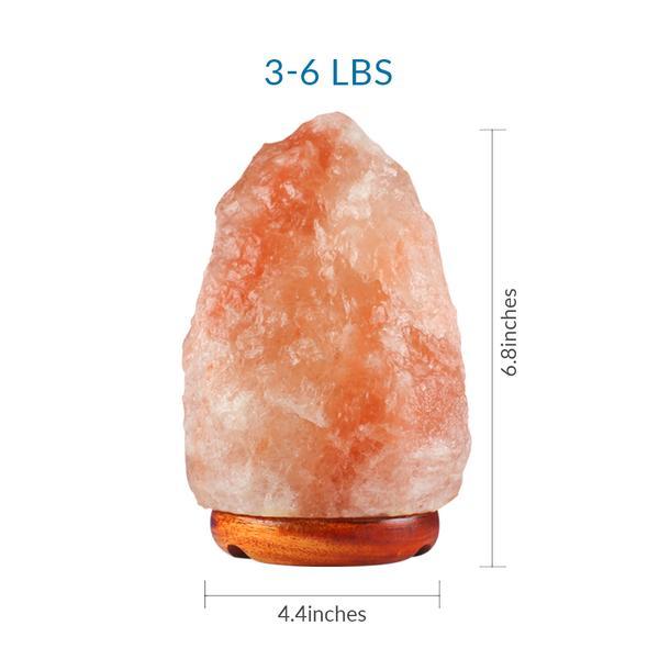 A set of four unique Himalayan salt lamps, each hand-carved with irregular shapes, showcasing hues of pink and orange, resting on polished wooden bases.