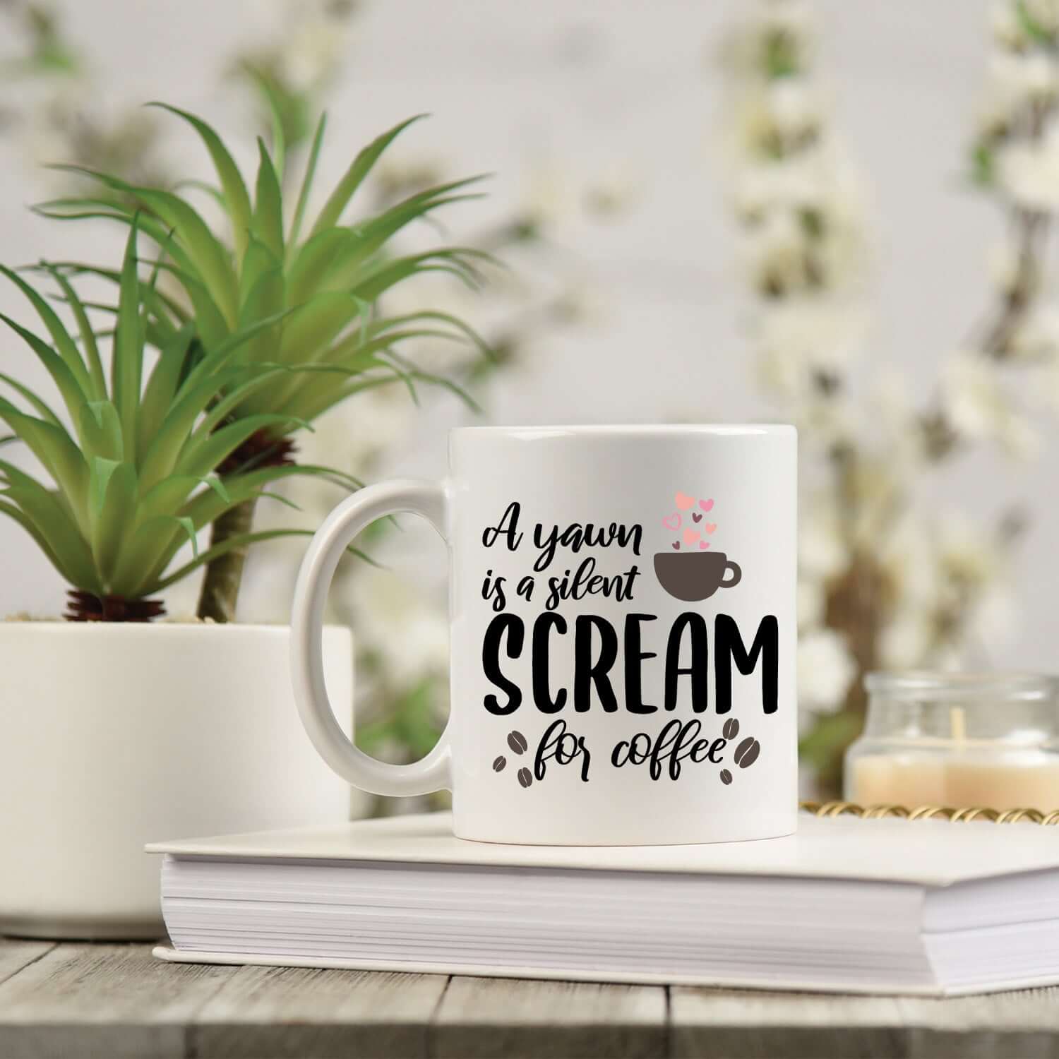 A glossy white ceramic mug with a vibrant print that reads 'A Yawn is a Silent Scream for Coffee', perfect for coffee and tea lovers.