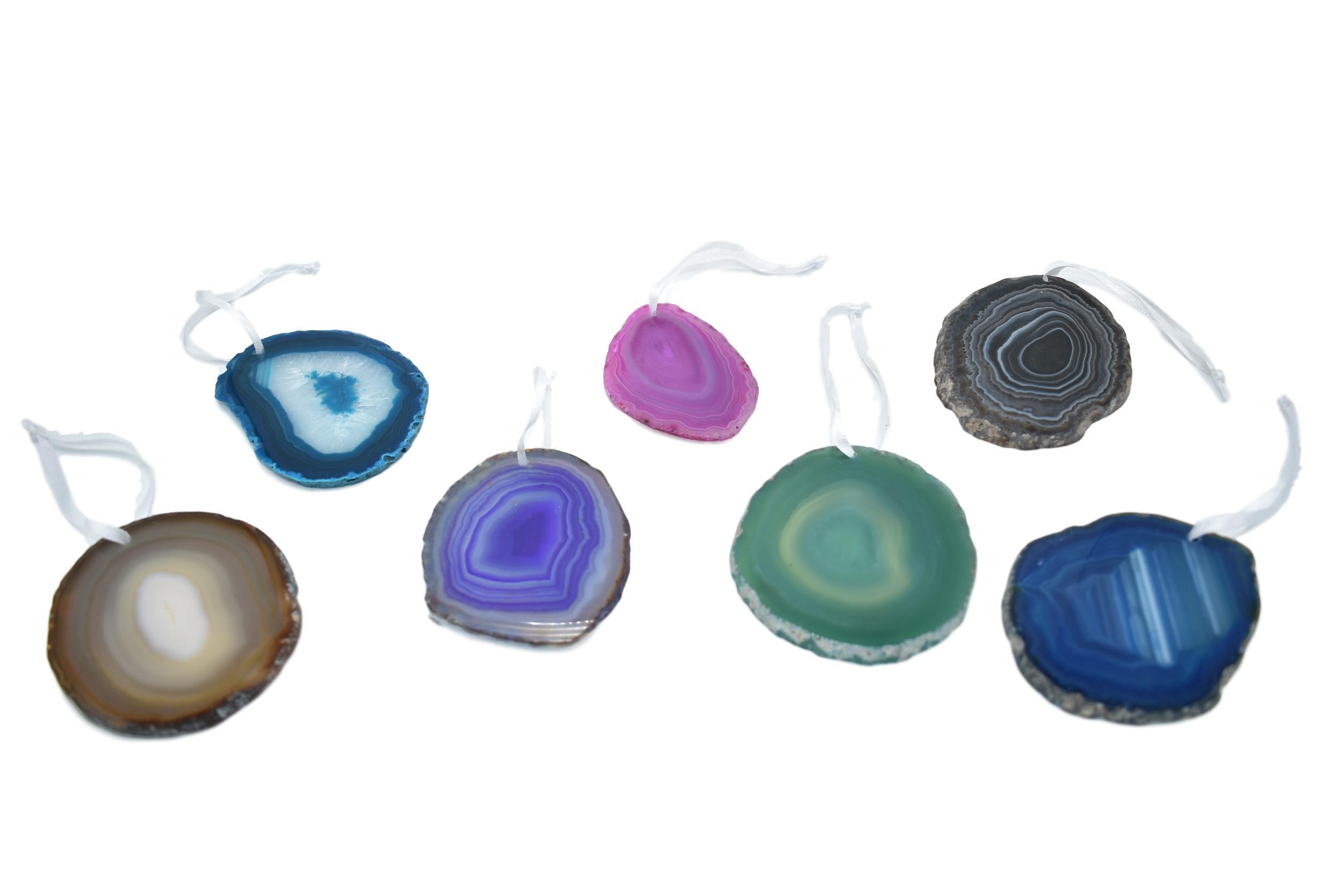 A beautiful agate ornament with a polished natural trim, hanging from a white silk ribbon, showcasing its unique colors and patterns.