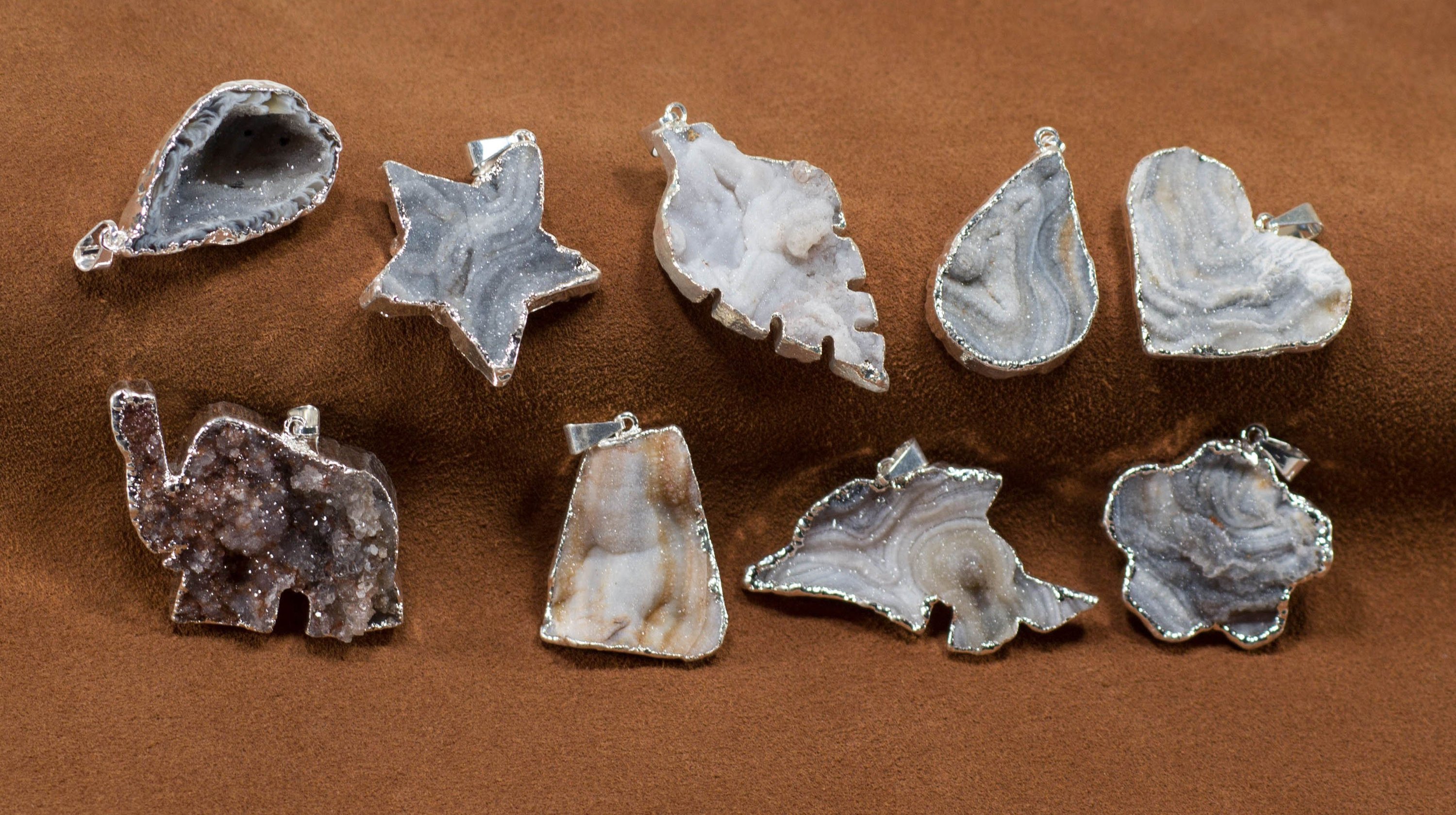 A collection of elegant agate sculpture pendants in various designs, including leaf, heart, and dolphin, trimmed in silver and gold.