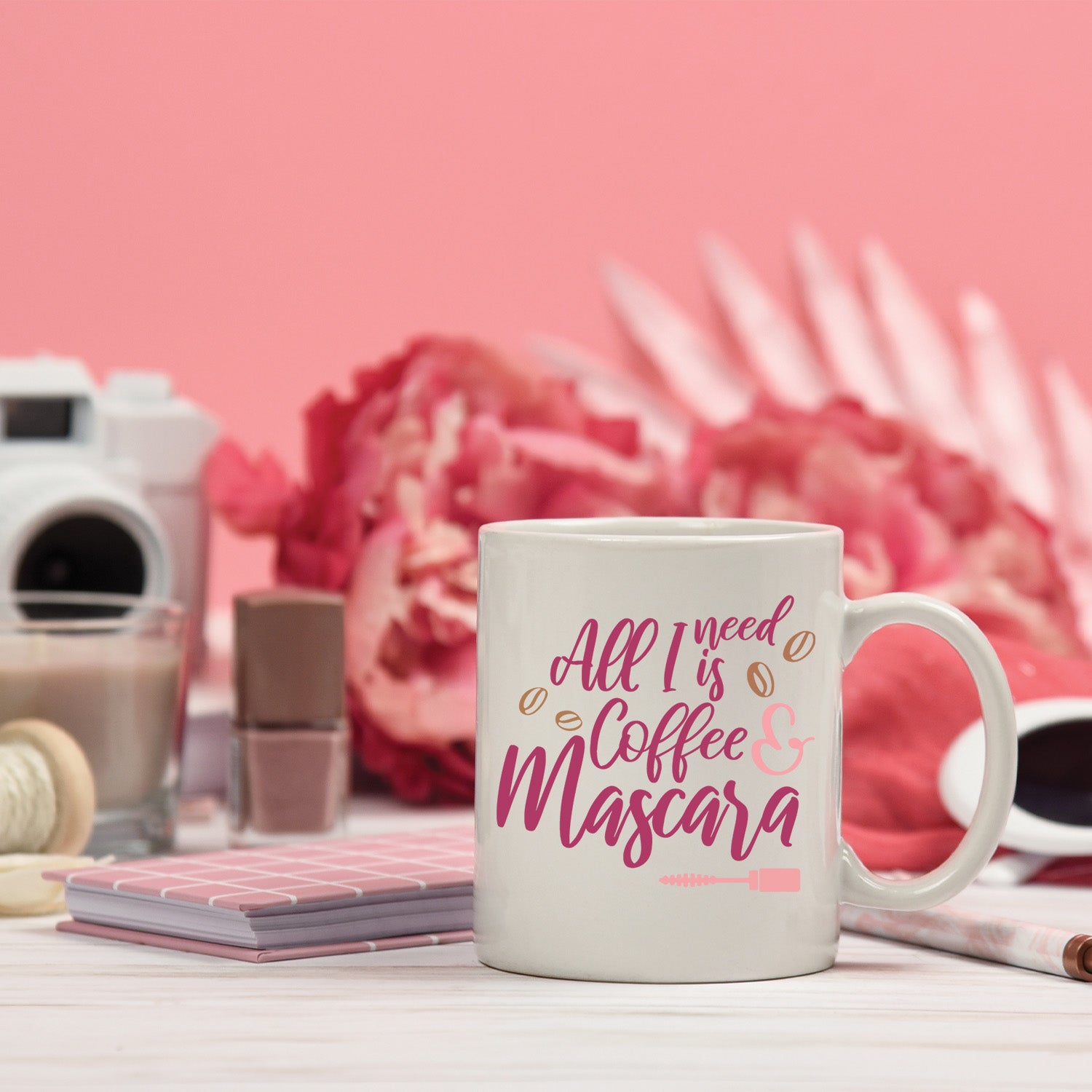 A glossy white ceramic mug with the phrase 'All I Need is Coffee and Mascara' printed in vibrant colors, perfect for coffee lovers.