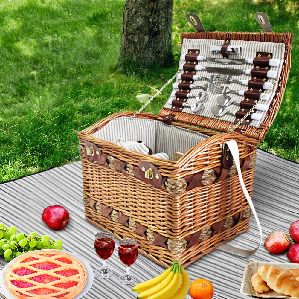 Alfresco 4 Person Picnic Basket made of willow with faux leather straps, filled with cutlery, plates, and a matching blanket, perfect for outdoor picnics.