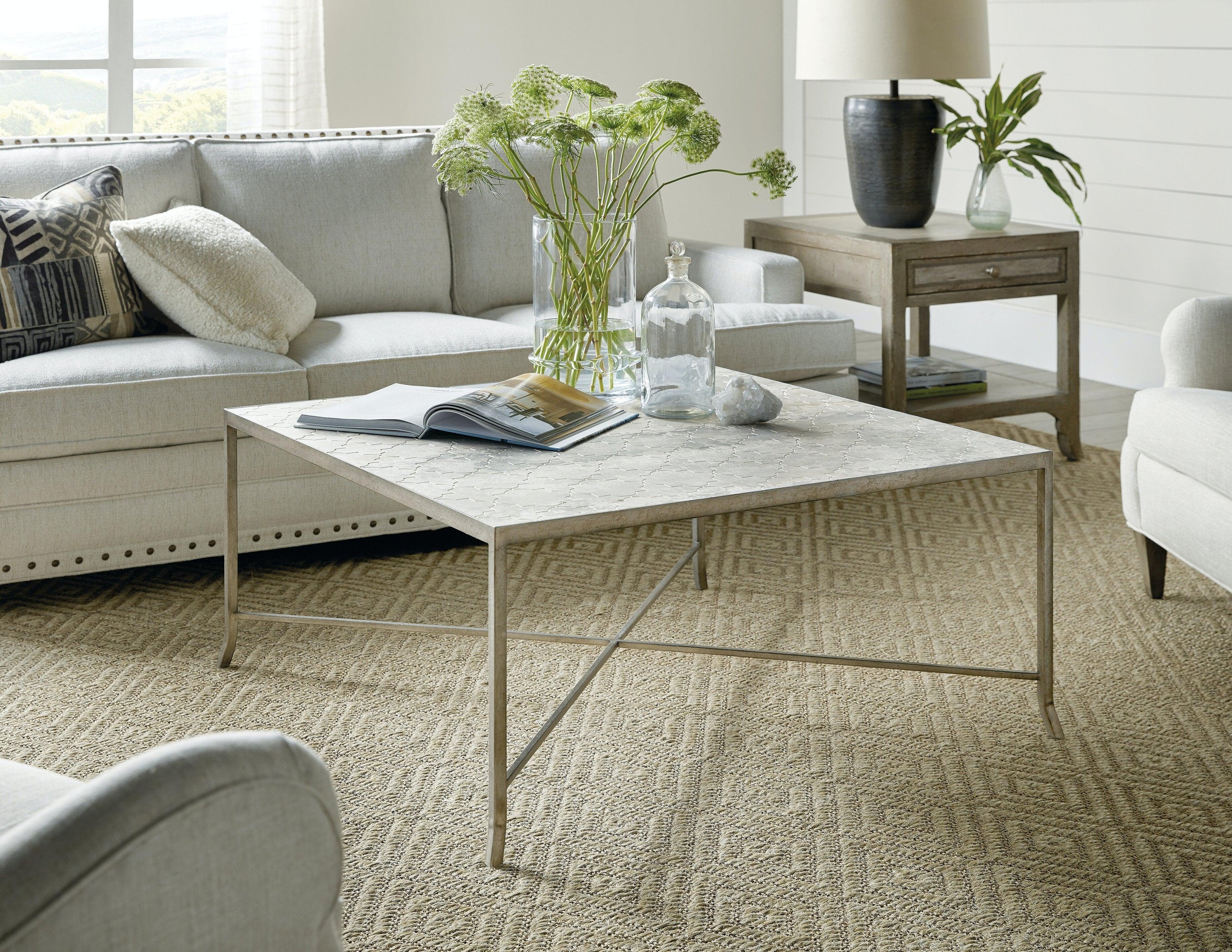 Alfresco Lapilli Carved Top Cocktail Table featuring a carved stone top and light silver metal base, showcasing a rustic yet elegant design.