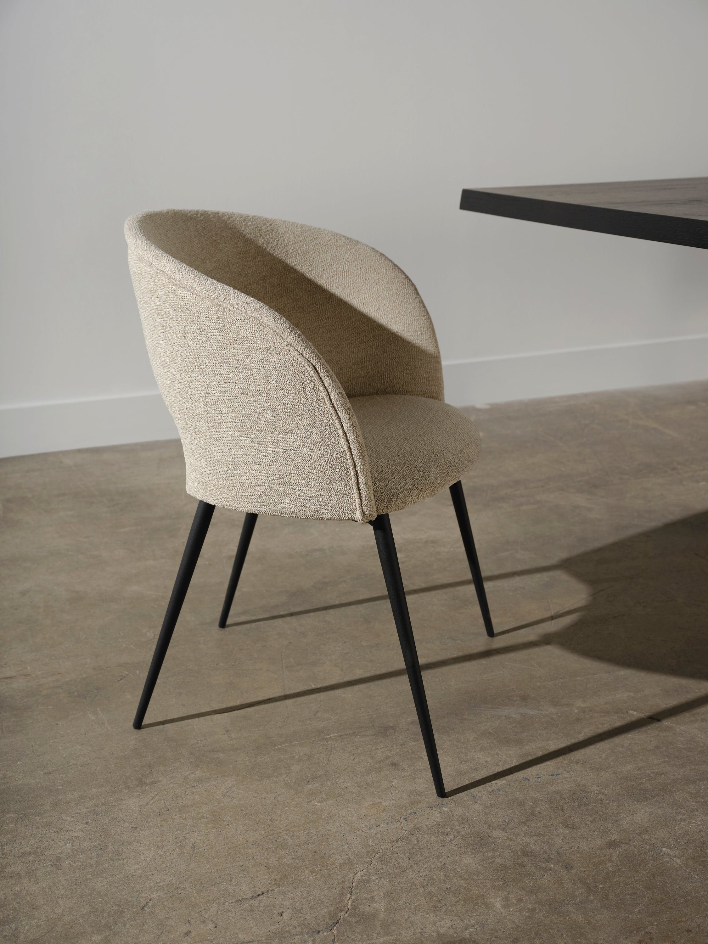 Alotti Dining Chair-Shell featuring a textured fabric seat and matte black steel legs, showcasing a retro design with a curved back.