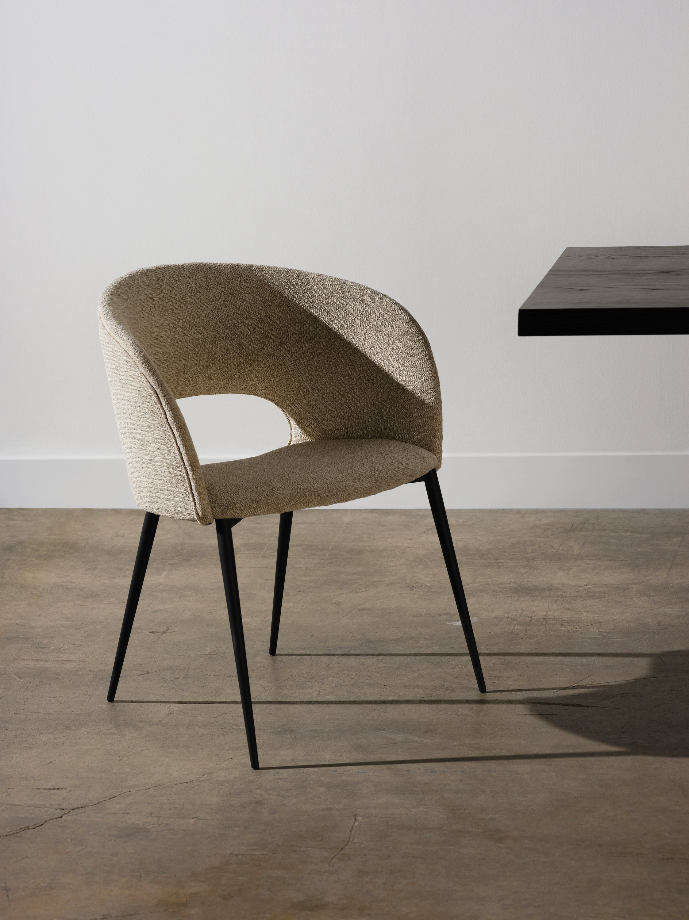 Alotti Dining Chair-Shell featuring a textured fabric seat and matte black steel legs, showcasing a retro design with a curved back.