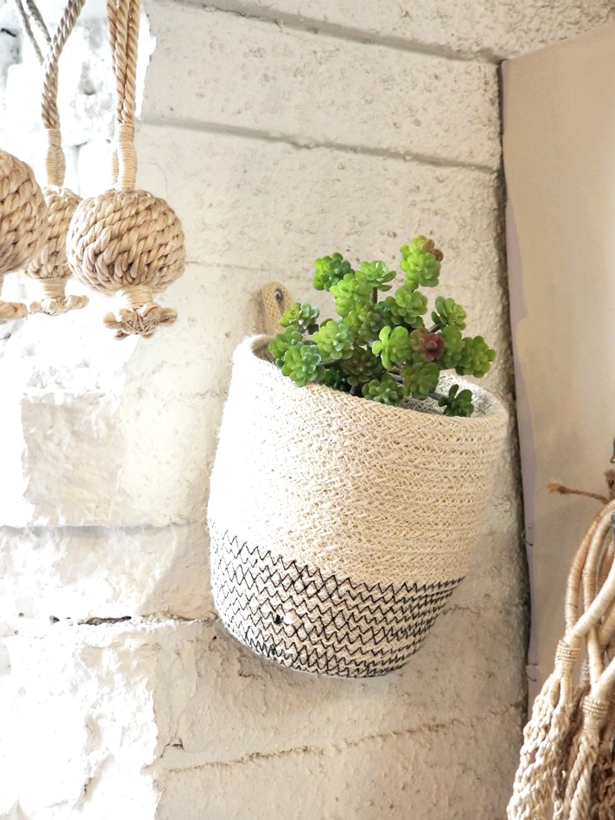 Amari Loop Bin in black with three thin bud vases, showcasing its handcrafted jute design.