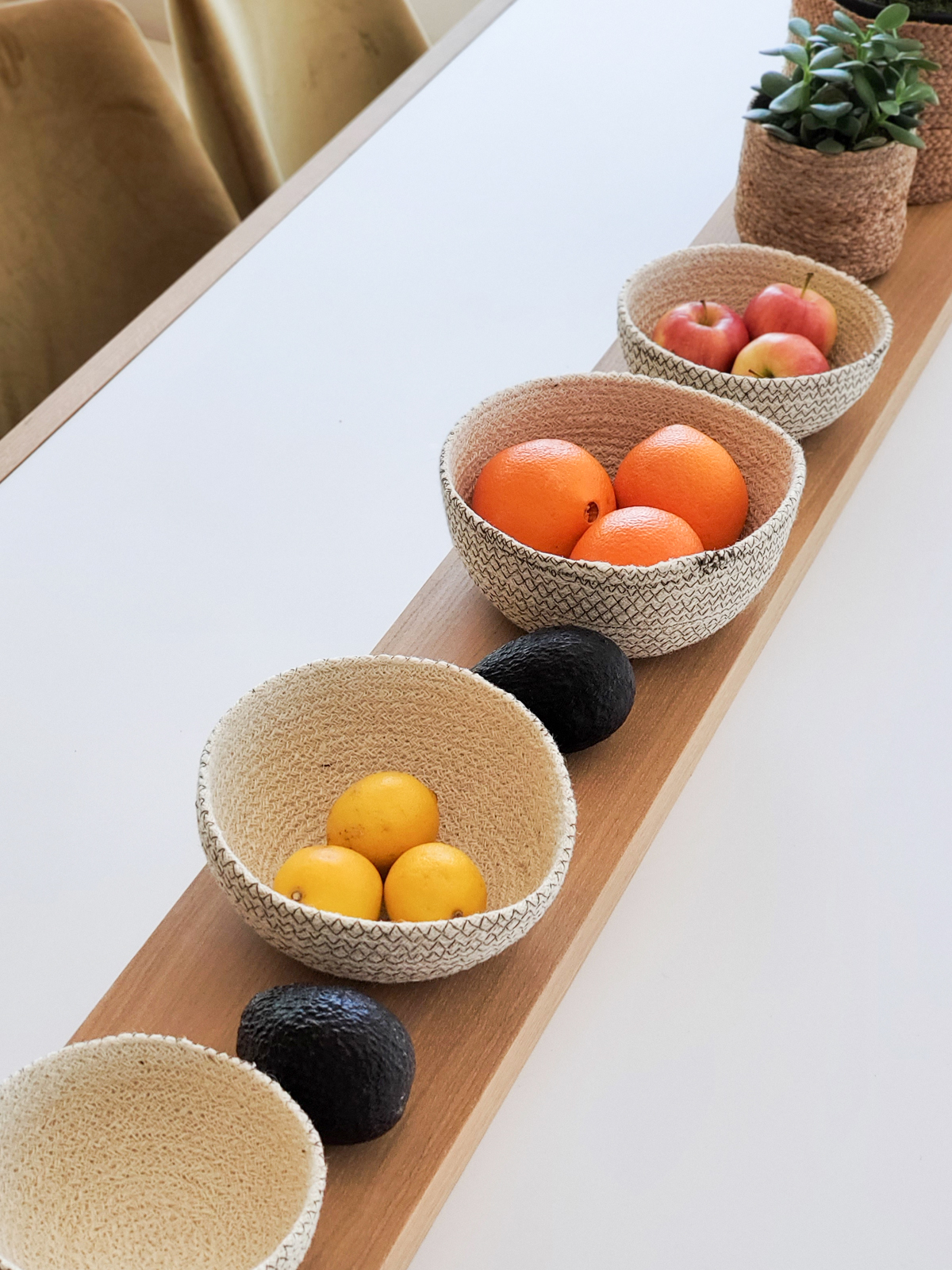 Set of four Amari Round Bowls in off-white with brown stitching, showcasing their handcrafted design and various sizes.