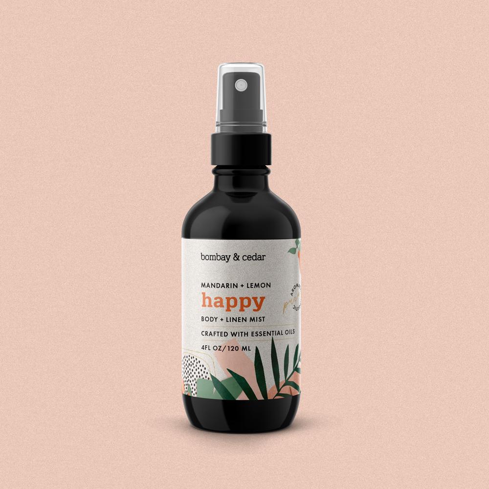 Aromatherapy Body + Linen Mist - Happy with citrus notes, in a spray bottle, surrounded by fresh citrus fruits.