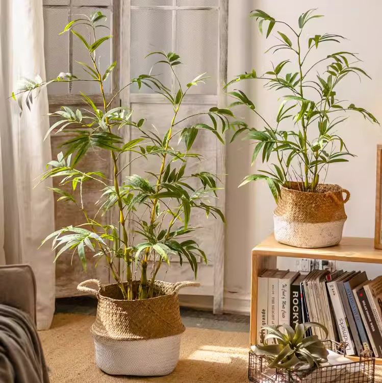 Lifelike artificial bamboo leaves in a black pot, showcasing vibrant green foliage.